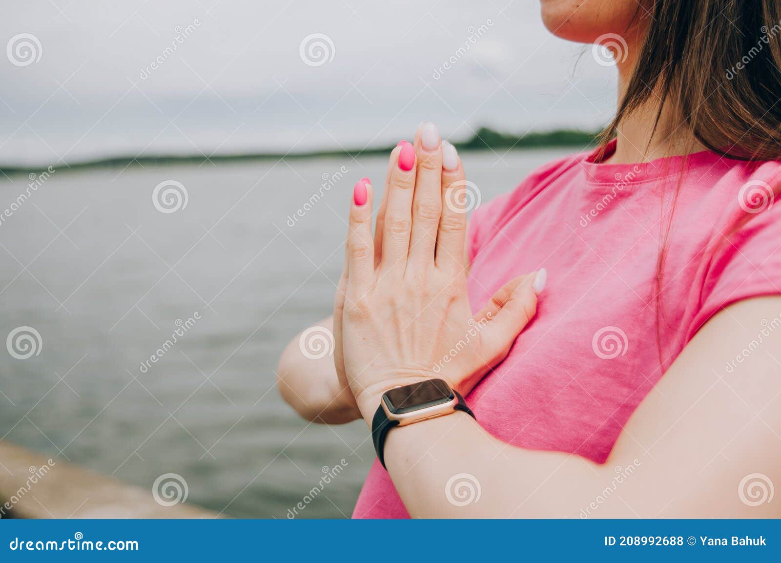 young brunette woman with bare feet  wearing black and purple fitness outfit  stretching on violet yoga mat outside on wooden pier