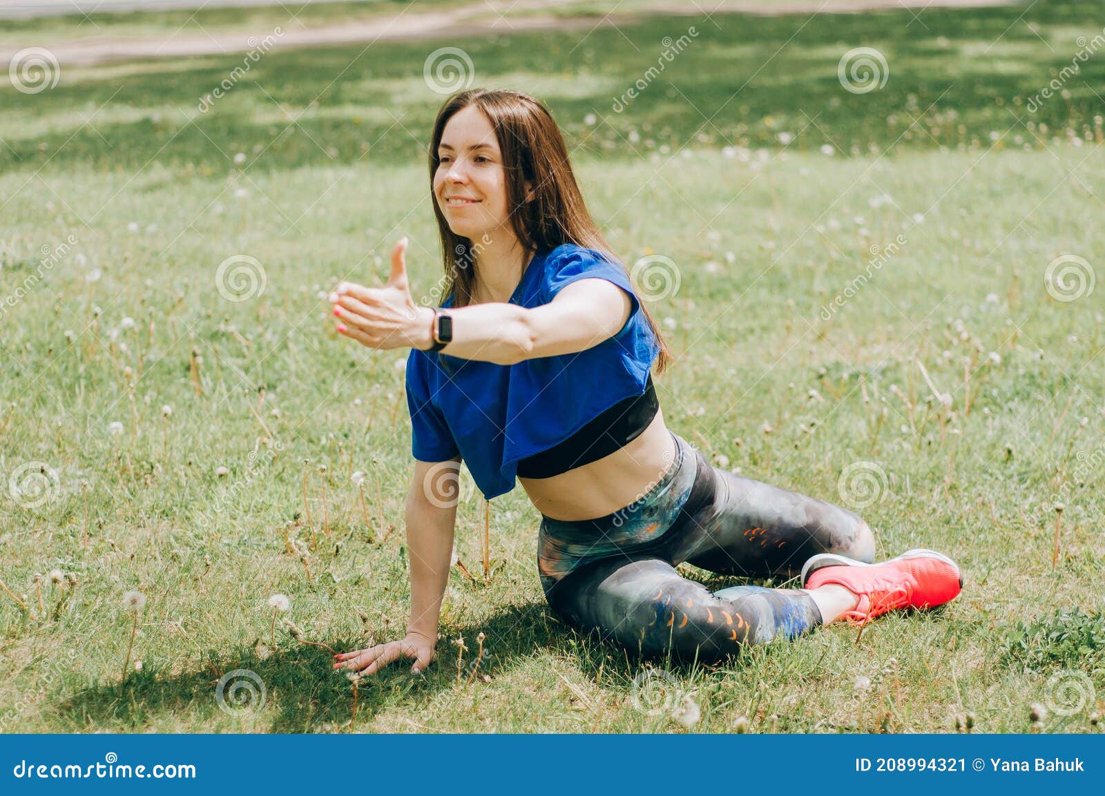 young brunette woman with bare feet  wearing black and purple fitness outfit  stretching on violet yoga mat outside on wooden pier