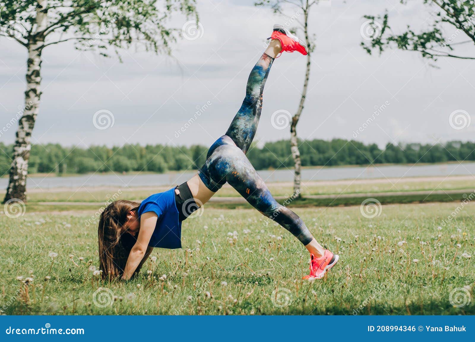 young brunette woman with bare feet  wearing black and purple fitness outfit  stretching on violet yoga mat outside on wooden pier