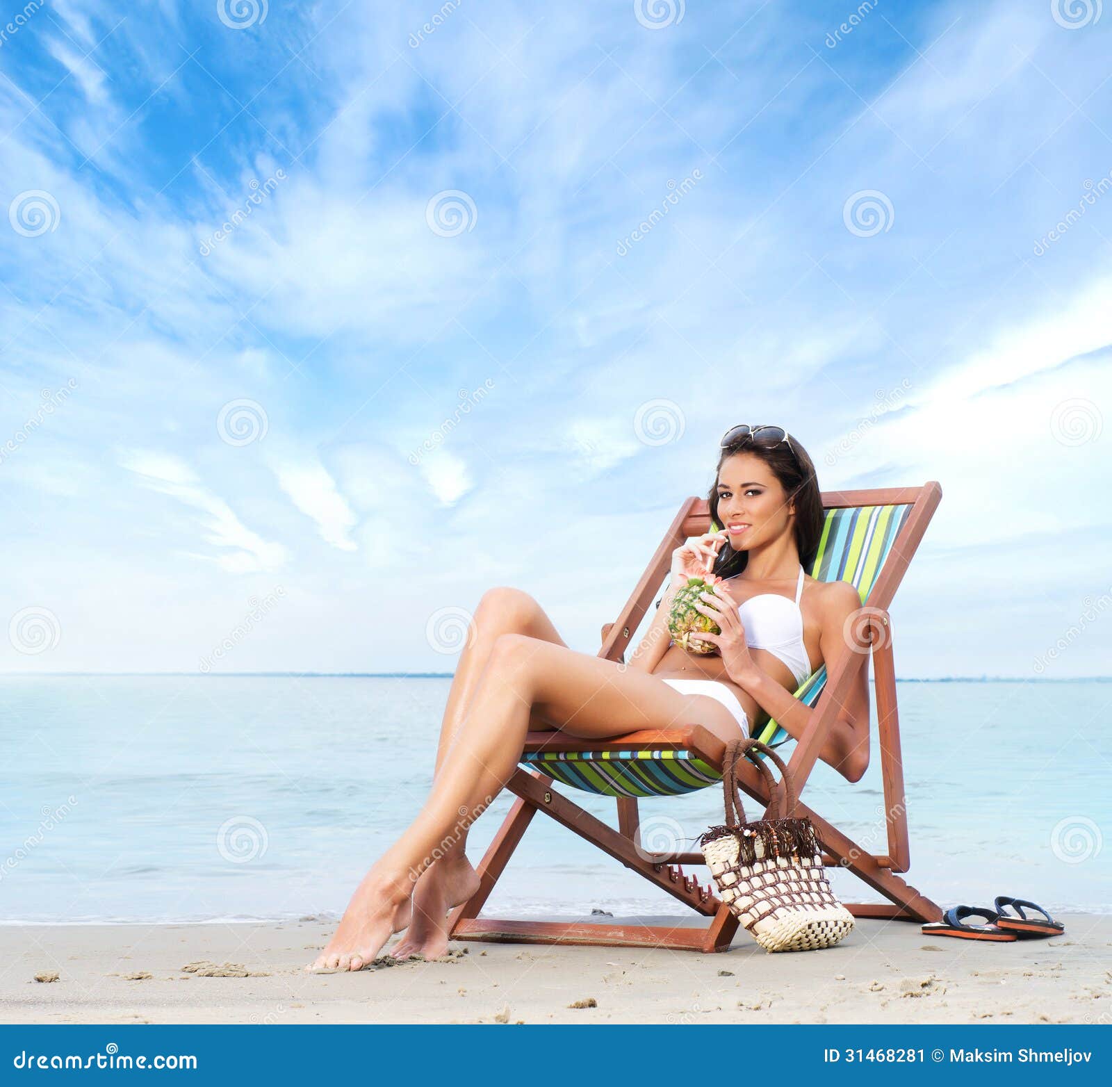 A Young Brunette Woman Drinking a Cocktail and Relaxing on the Beach Stock Image picture
