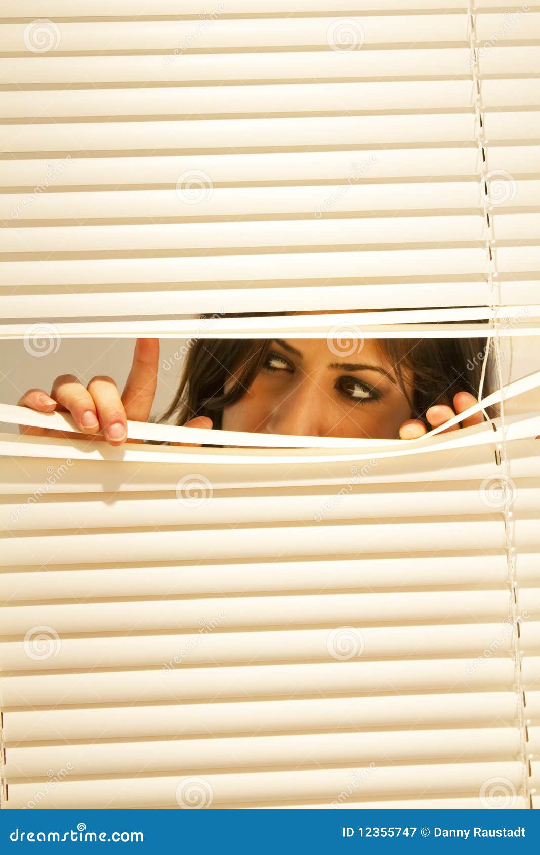 young brunette woman looking through window blinds