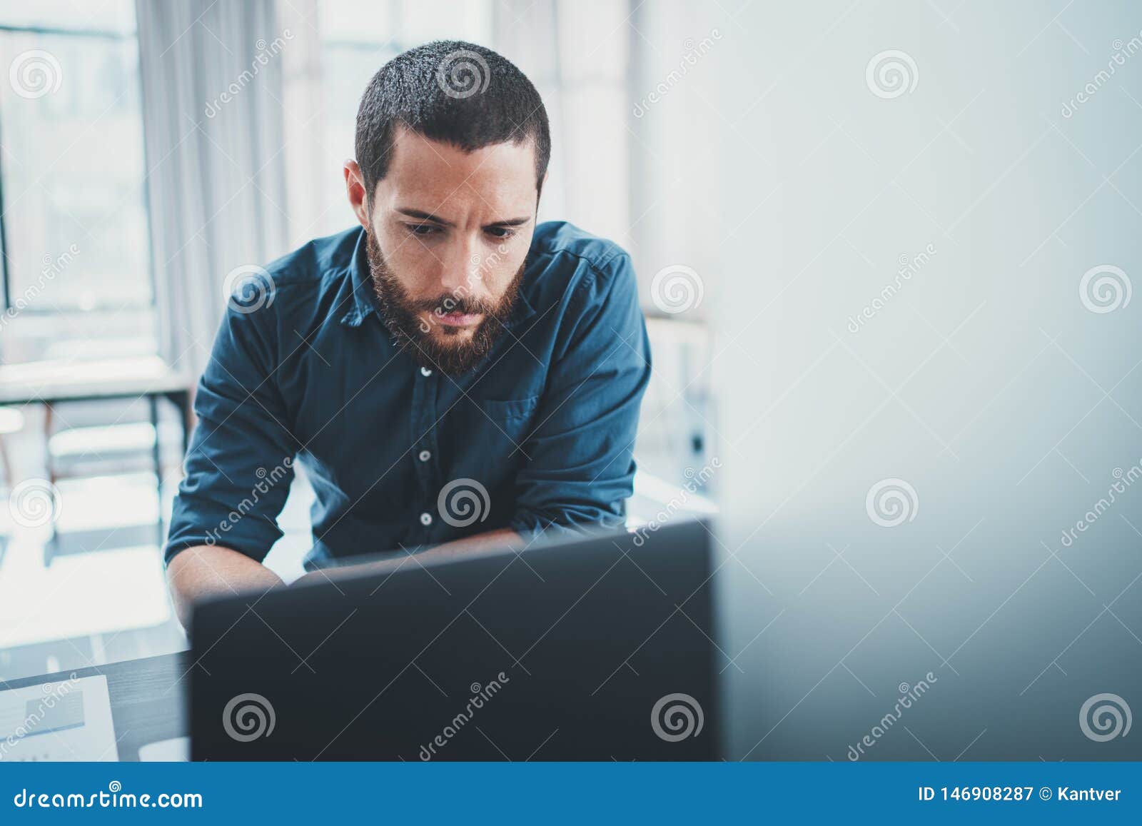 young business man working at lightful office on computer while sitting at the wooden table.