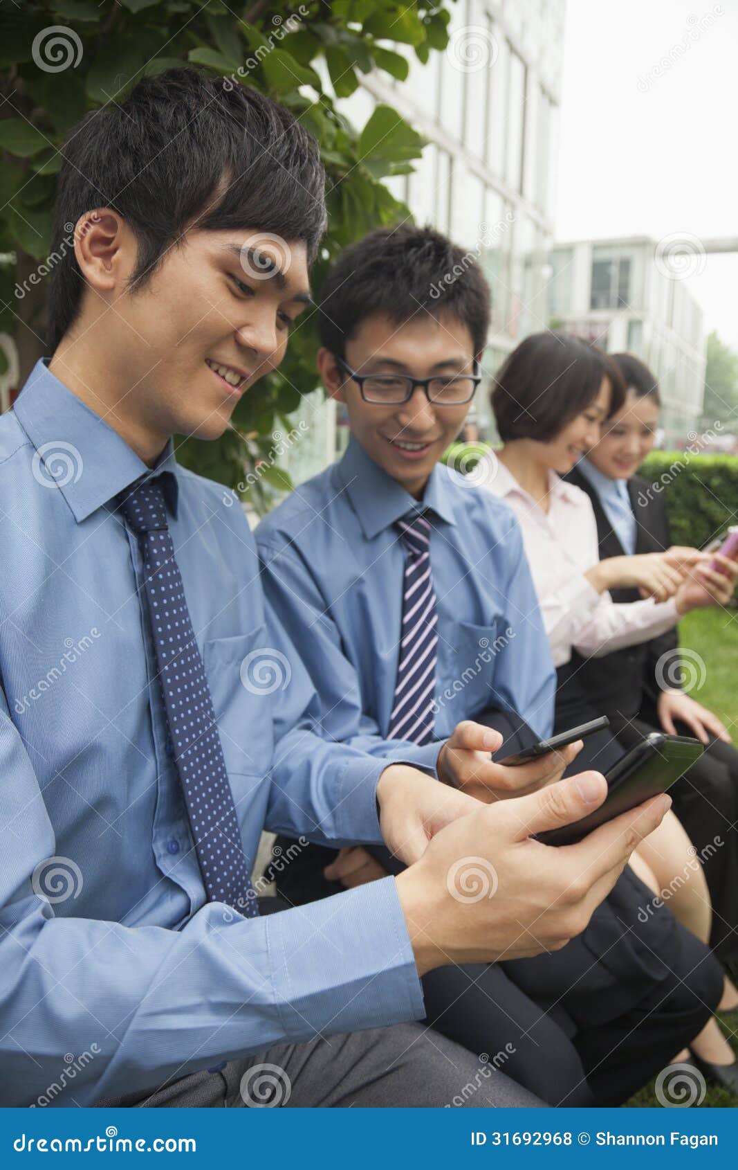 Group Of Young Asian People Sitting And Addicted To Playing Mobile