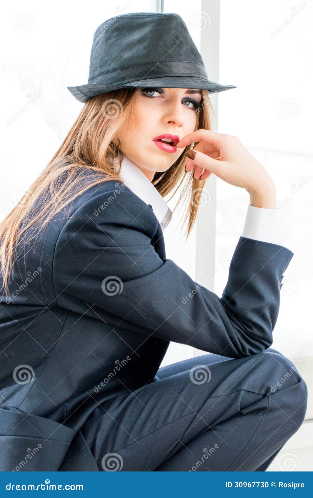 Young Business Woman Wearing Man's Suit, Hat In Office Stock Photo
