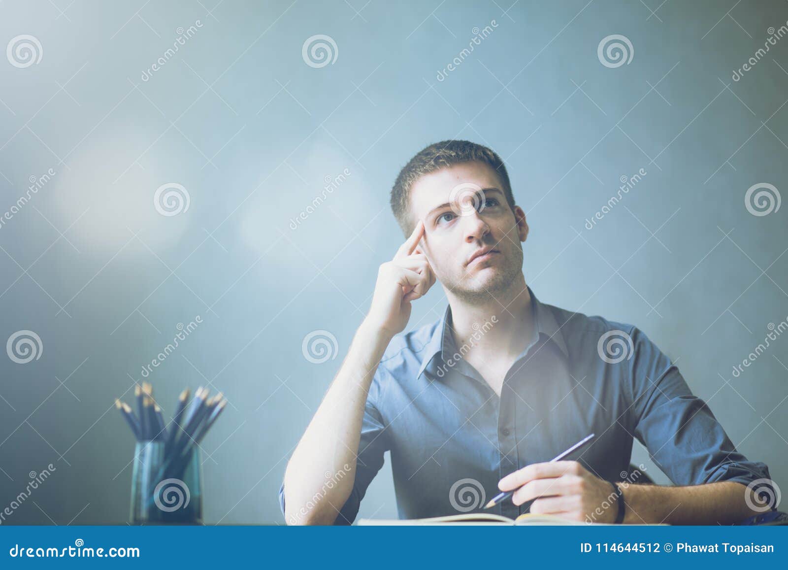 young businessman caucasians sitting at desk office table and taking notes in notebook. writing and looking to right hand side