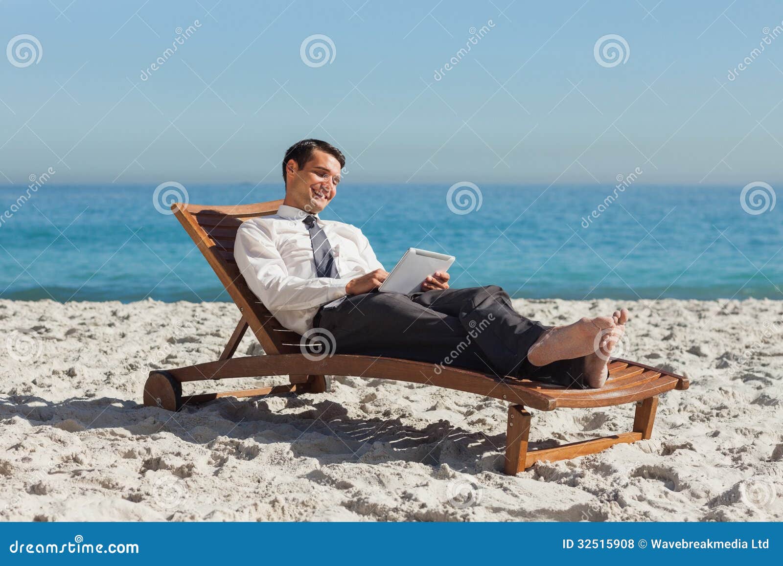 Young Businessman Relaxing on a Deck Chair Using His Tablet Stock Photo ...