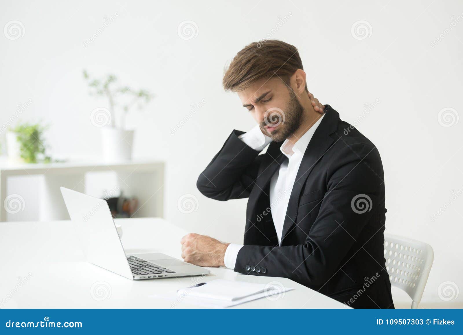 young businessman in suit feeling neck pain after sedentary work