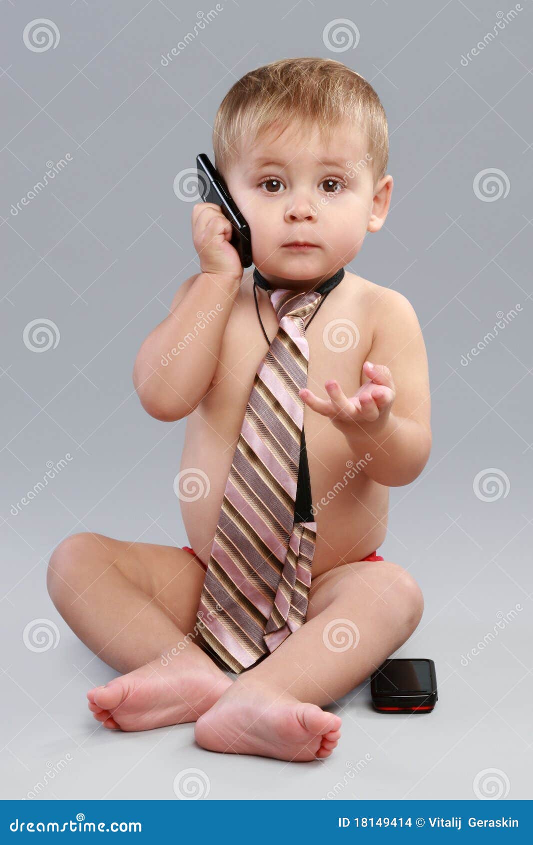 Young businessman talk on cell phone in a tie, on a grey background