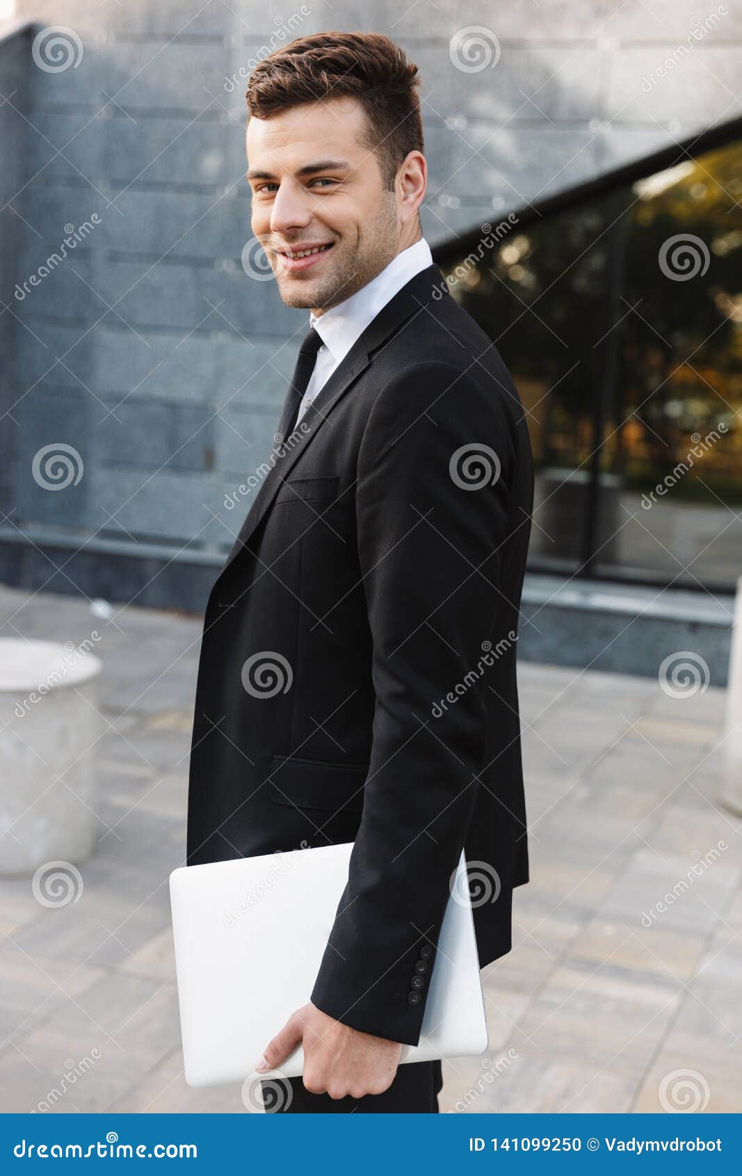 Young Businessman Walking Outdoors at the Street with Laptop Computer ...