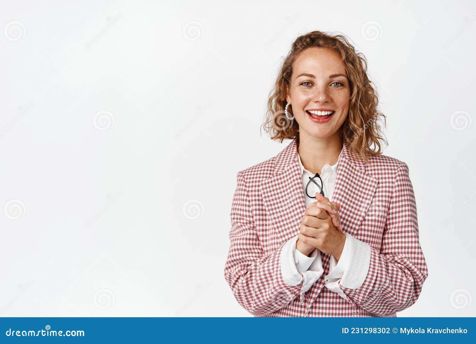 young businesswoman clench hands, looking with hopeful face expression, smiling and looking at camera with anticipation