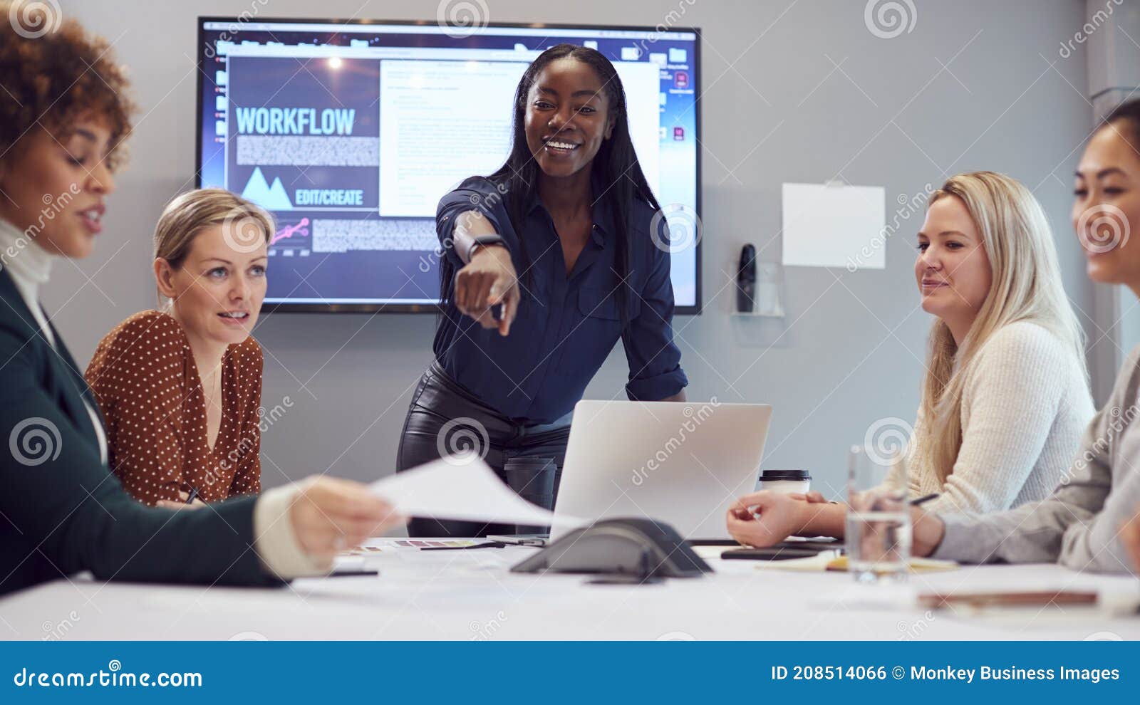 young businesswoman leading creative meeting of women collaborating around table in modern office