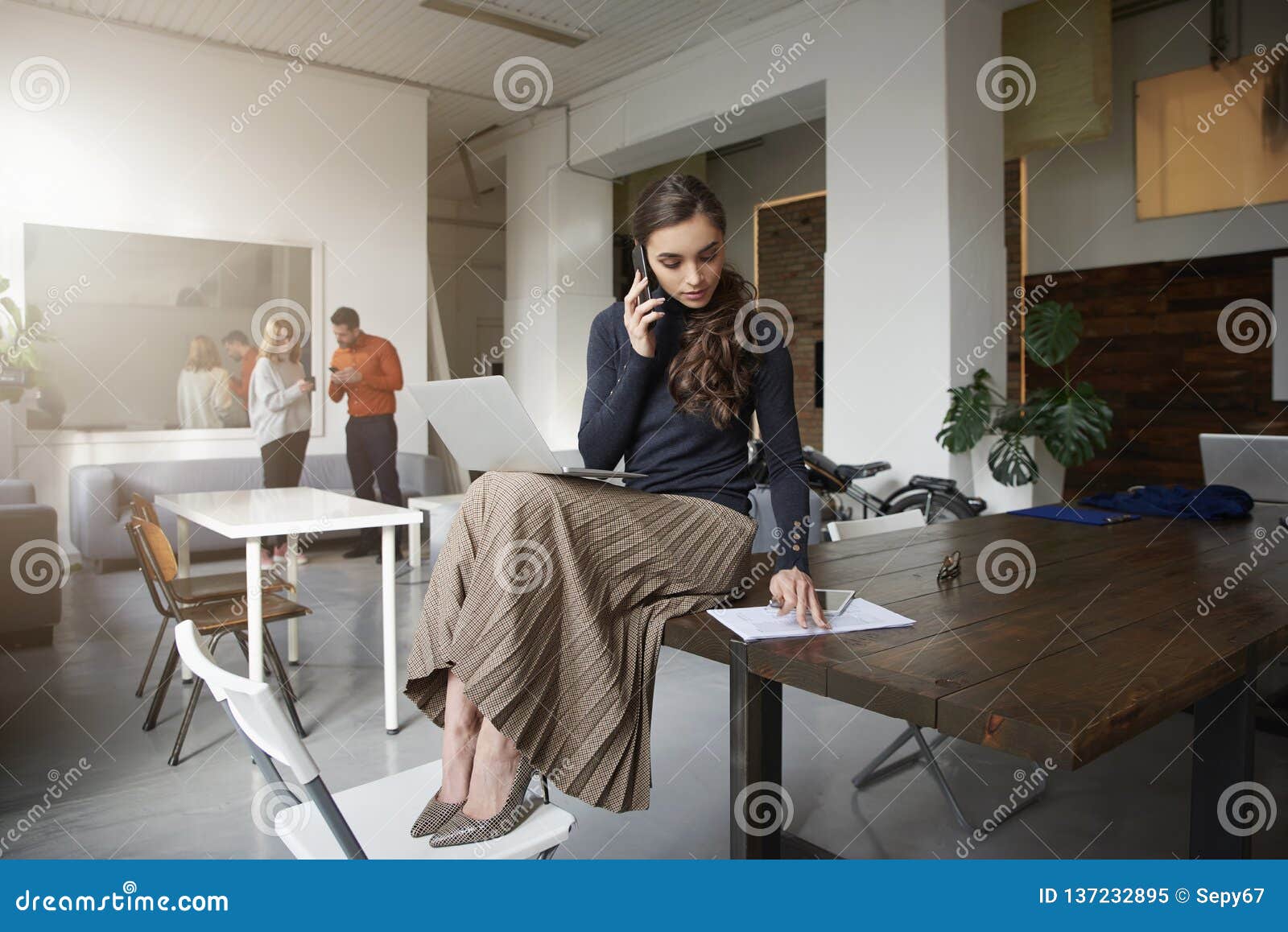 Young Businesswoman Making a Call while Sitting on Office Desk and ...