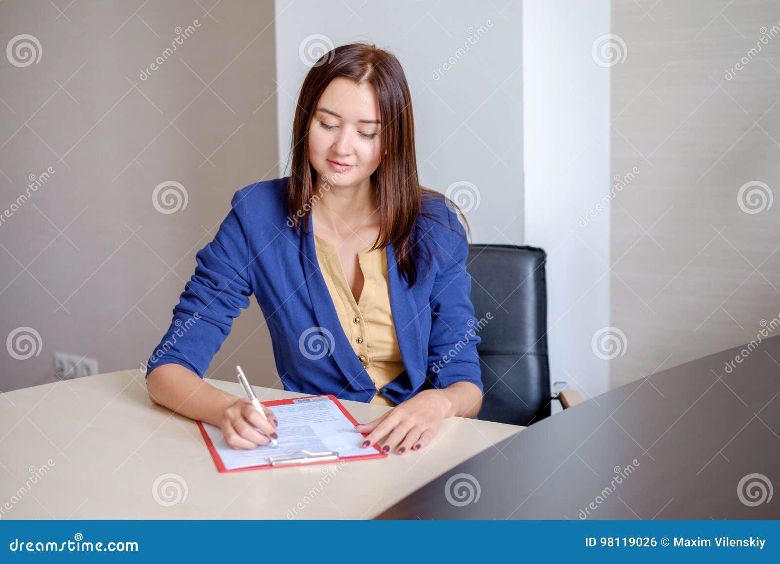 Young Businesswoman Working At Desk In Office Taking Notes Into