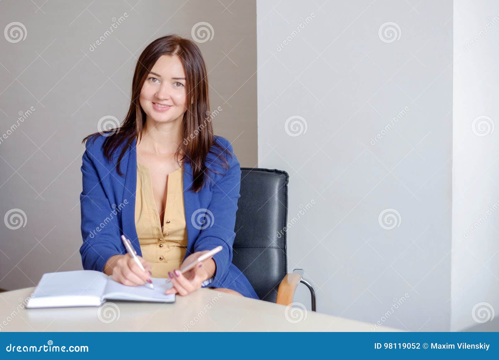 Young Businesswoman Working At Desk In Office Taking Notes Into