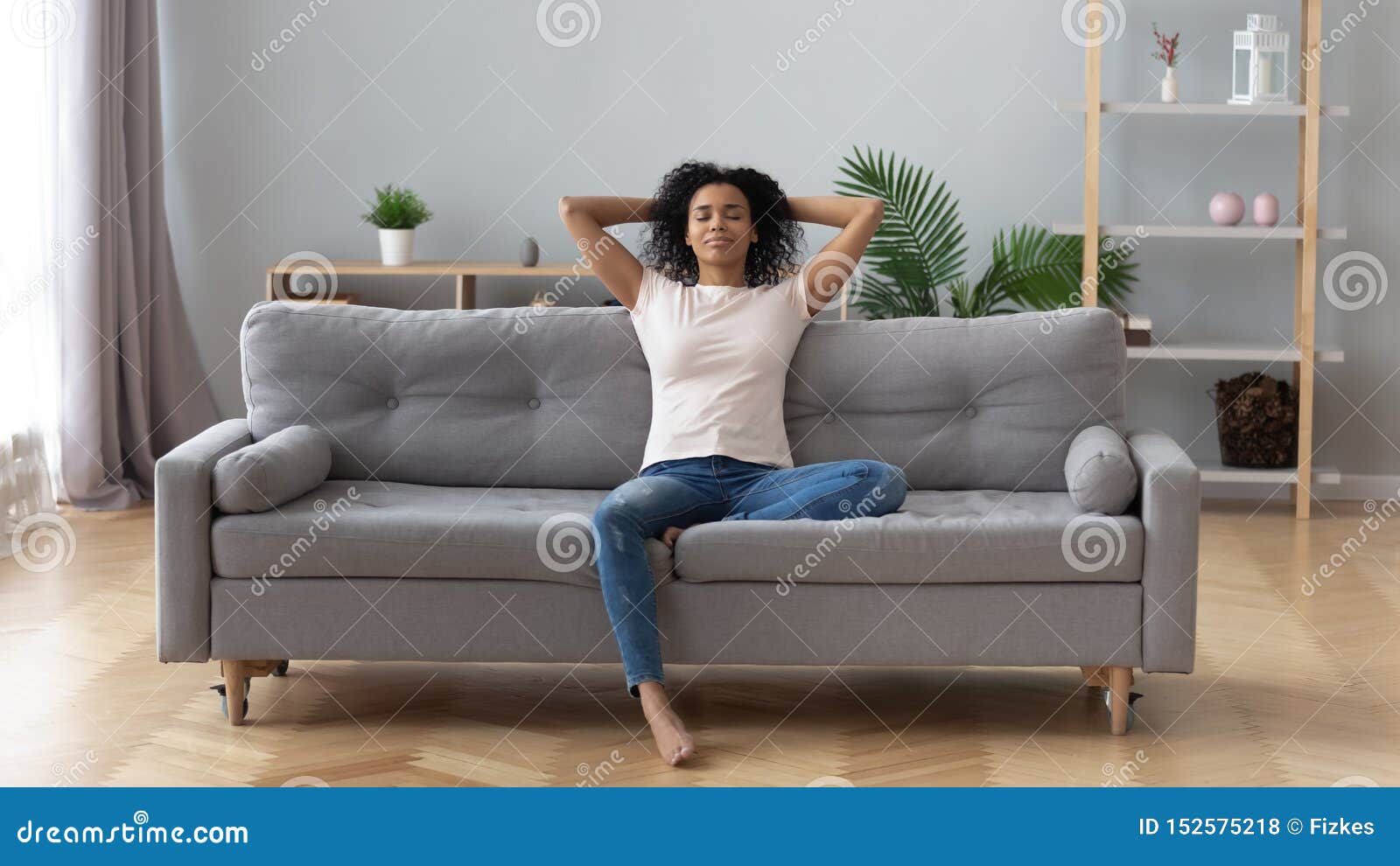 calm black woman relaxing on comfortable sofa in living room