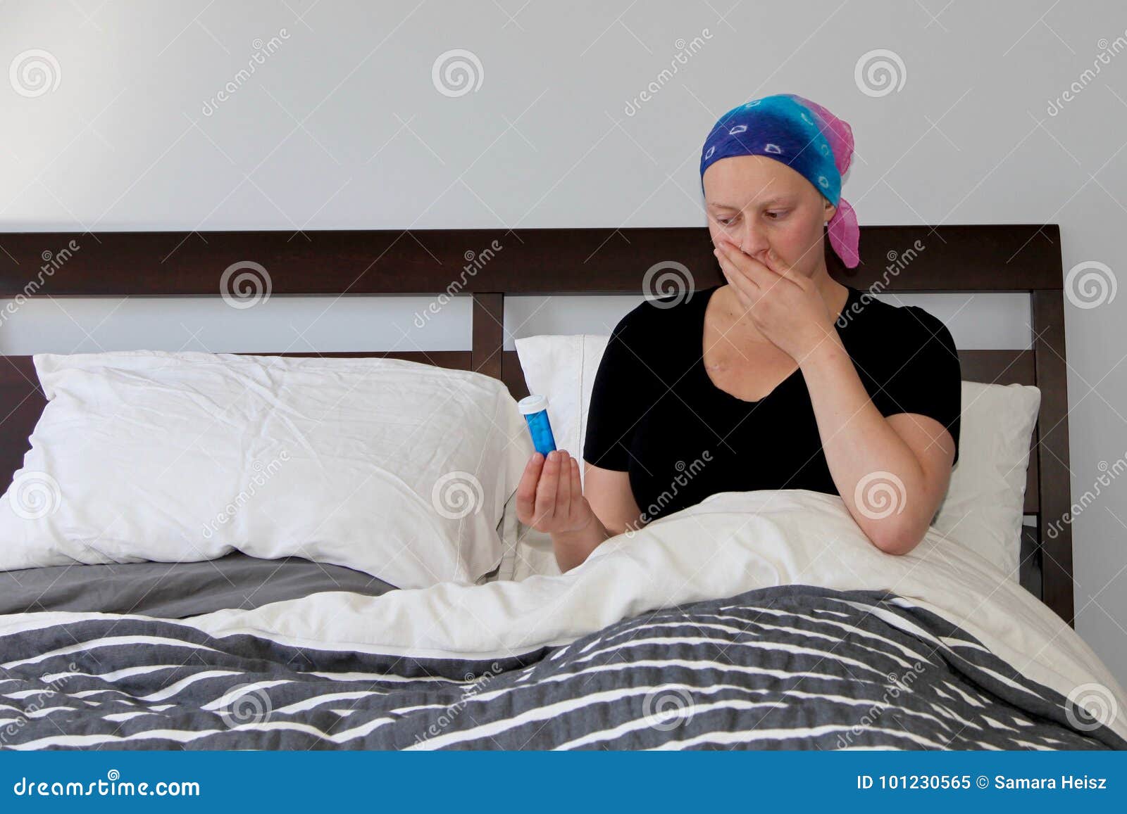 Young Cancer Patient In A Headscarf Rests In Bed With Nausea