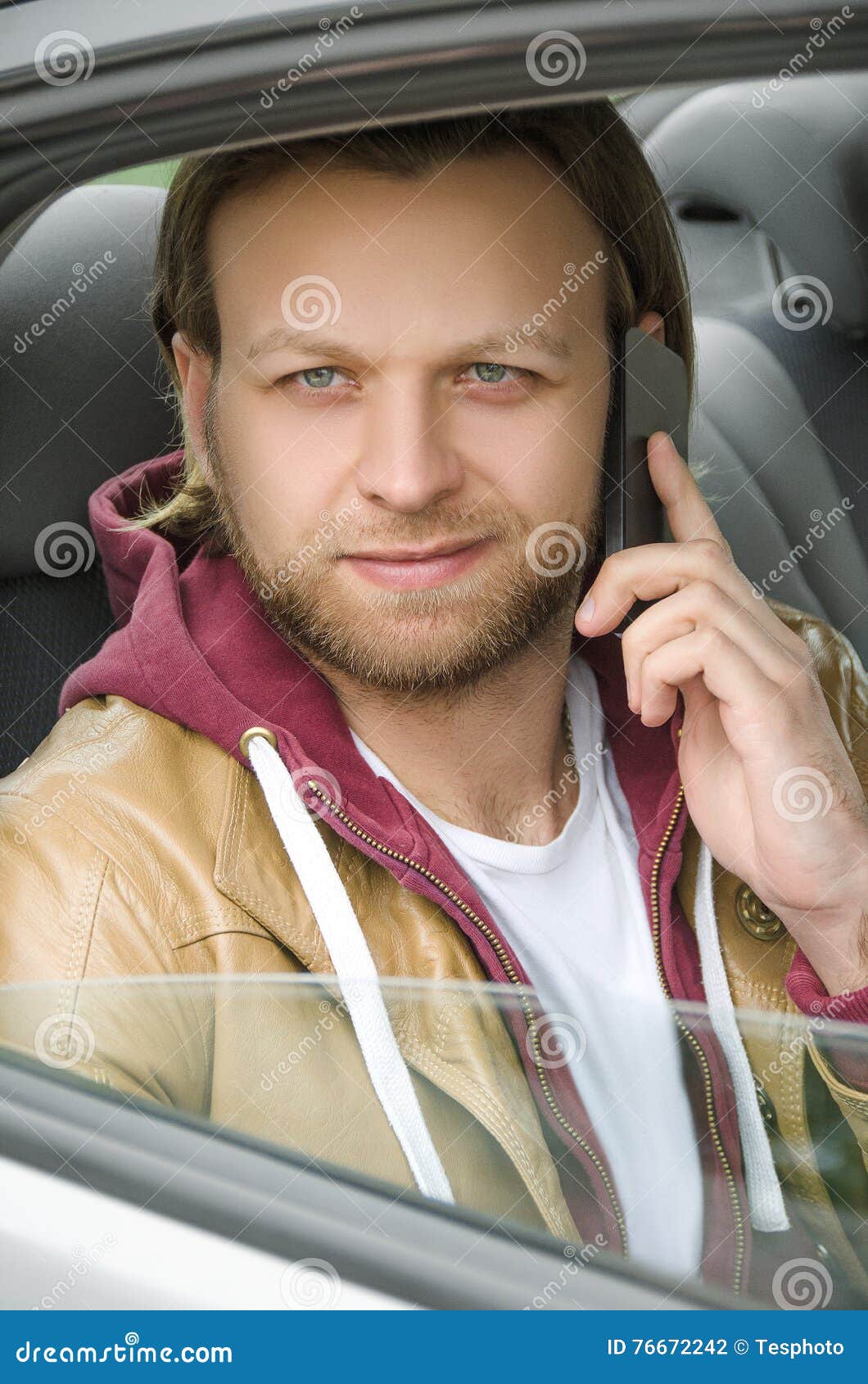 Young casual man smiling and talking on the mobile phone in car. Young casual man talking on the mobile phone in car.