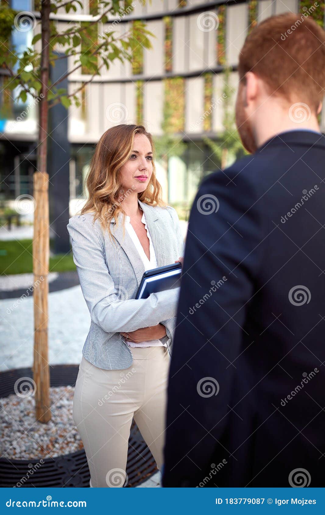 young caucasian businesswoman looking curiously  her interlocutor outdoor in front of business building. outdoor, unofficial,