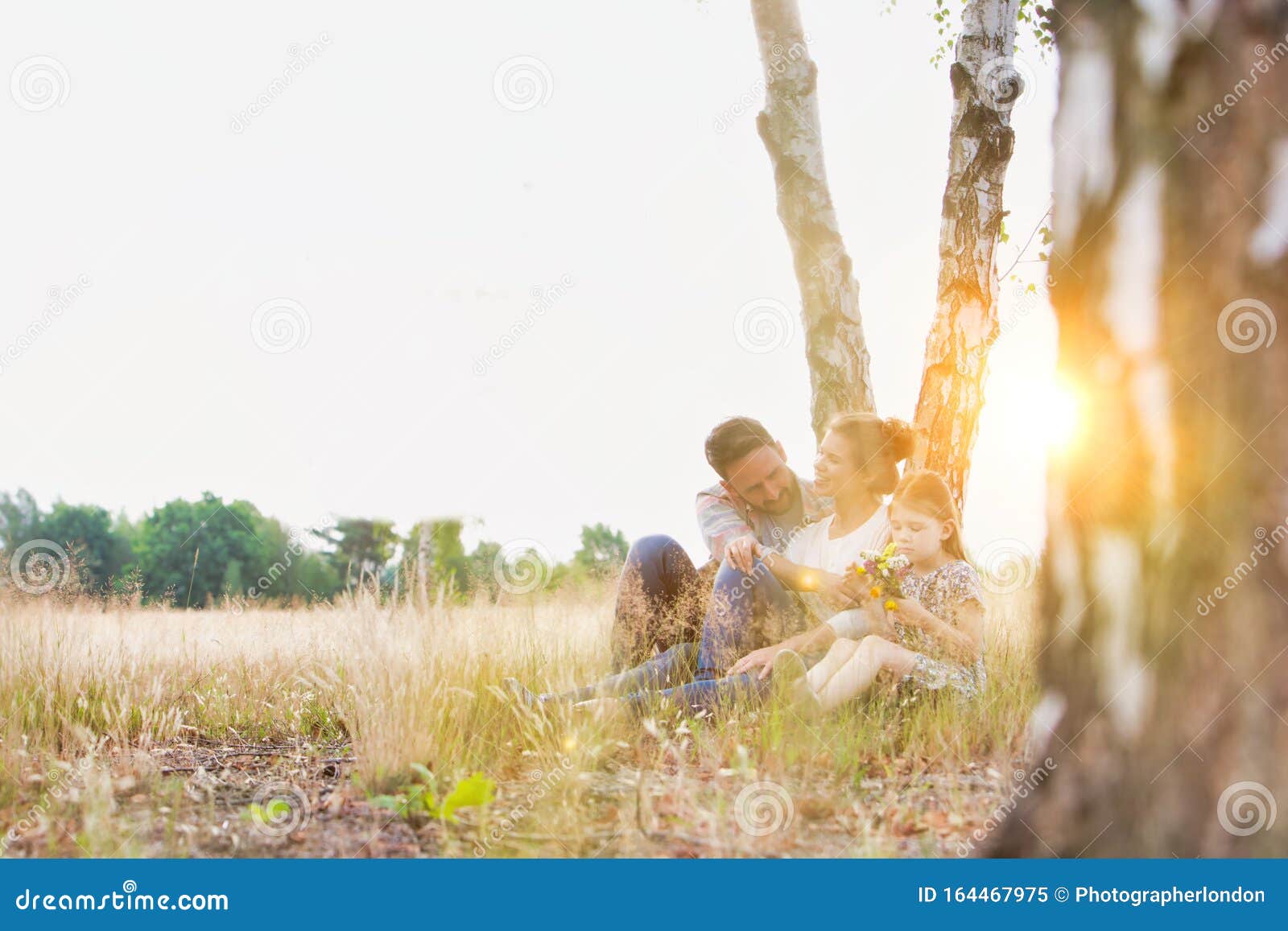 young caucasian family walking across field with young girl holding bouquet of flowers, concept organic ecologically friendly fami