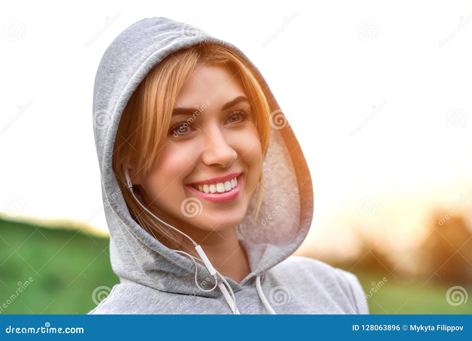 Young caucasian female jogger with earphones listening a music. Beautiful young woman with headphones glad after nice jogging in city park