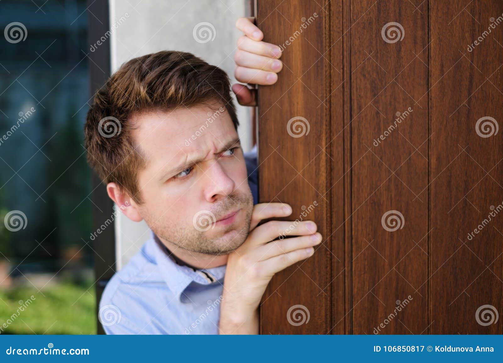 Young Caucasian Man With Agoraphobia Spying And Looking Out The Door