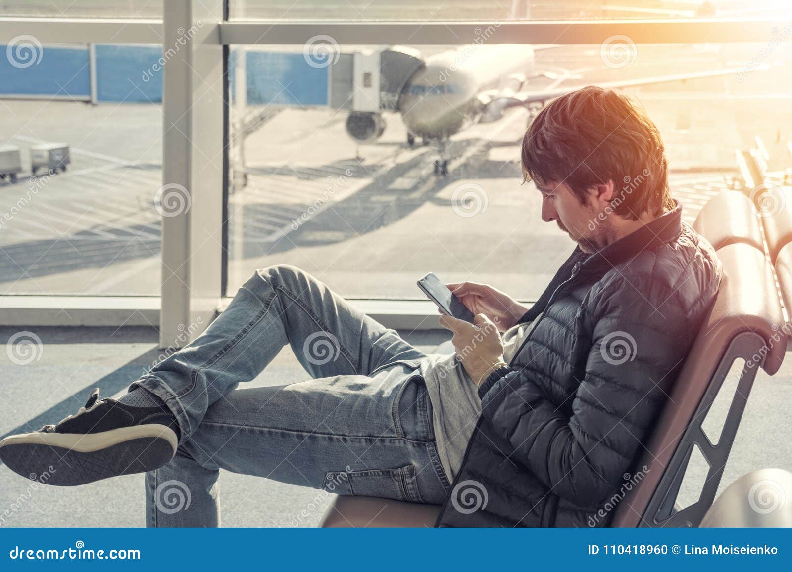 september Neuken maak het plat Young Caucasian Man in Jeans and Jacket Sitting in Airport Waiting Lounge  Hall, Using Mobile Phone. Stock Photo - Image of departure, contact:  110418960