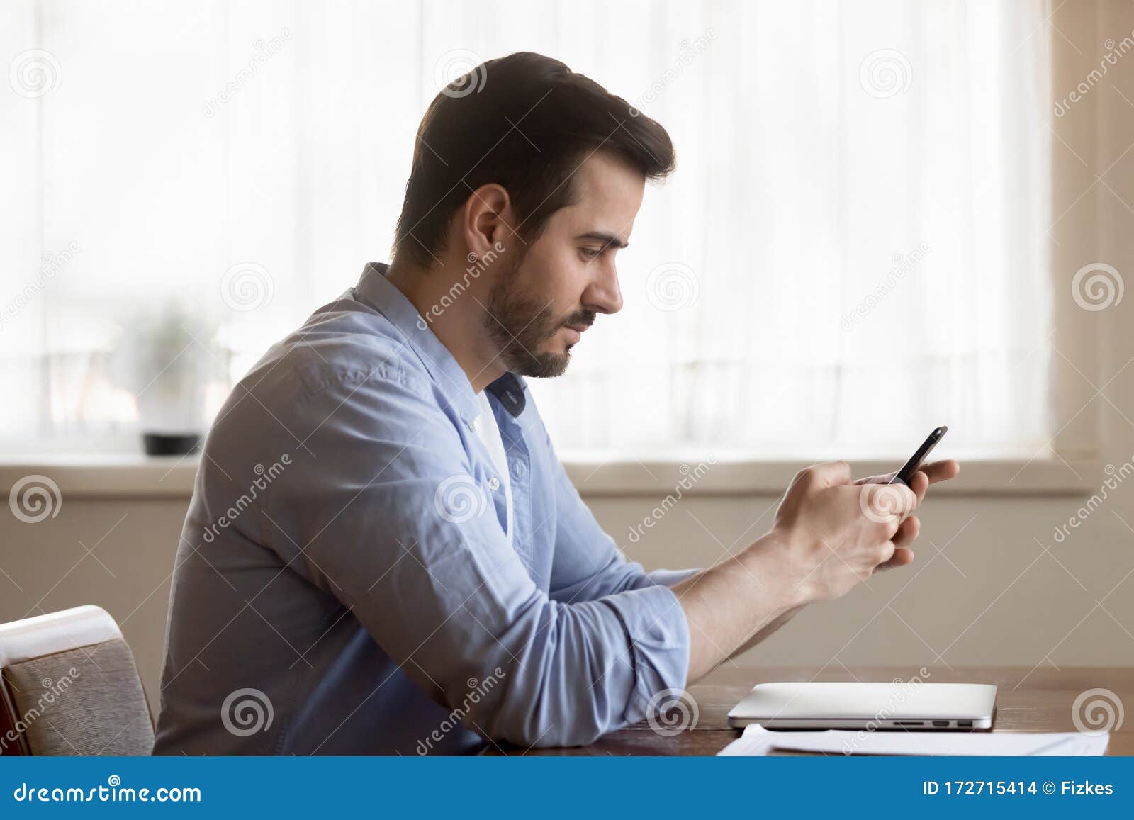 focused caucasian man sit at table using smartphone