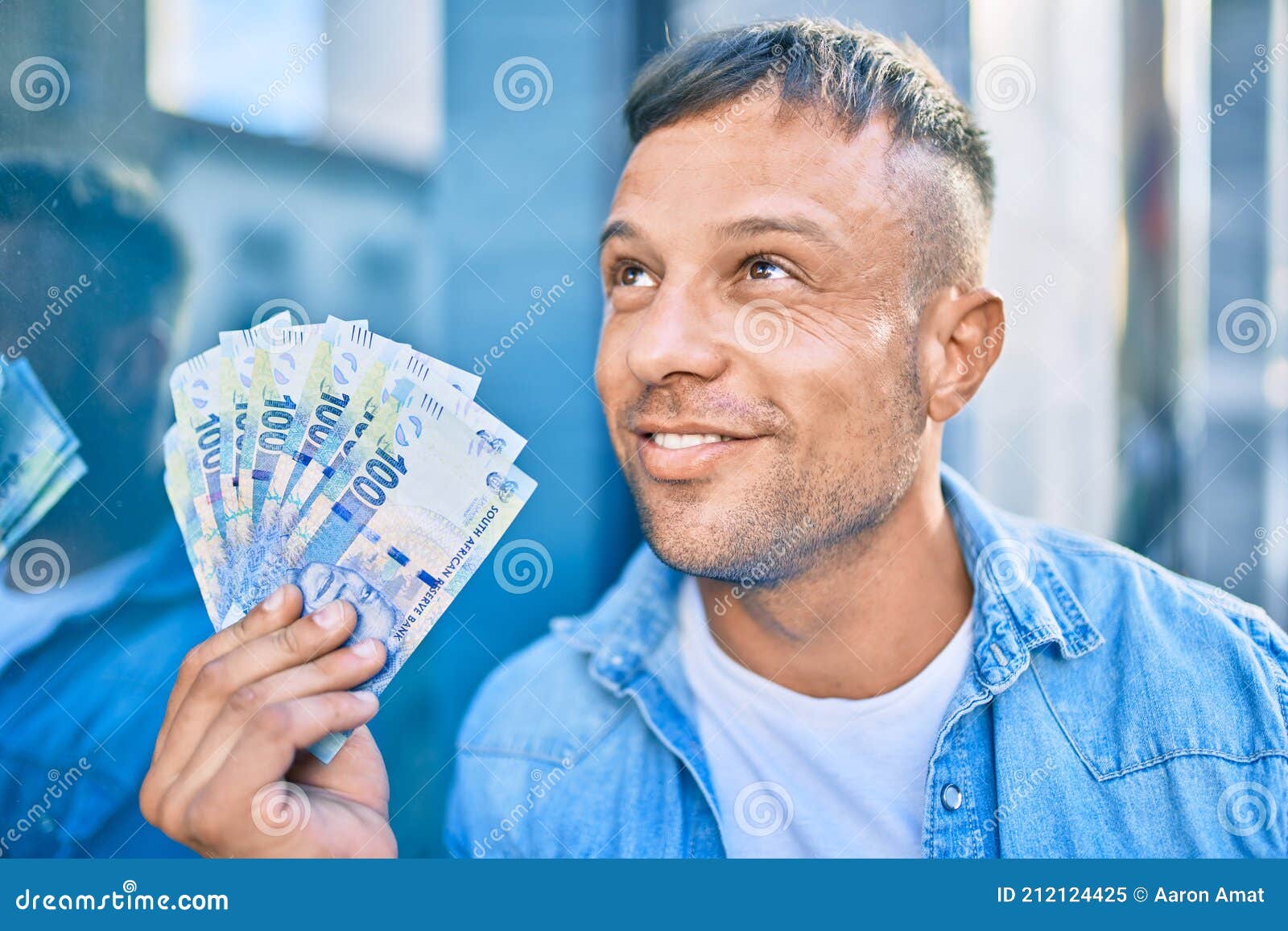 young caucasian man smiling happy holding south african rands banknotes standing at the city