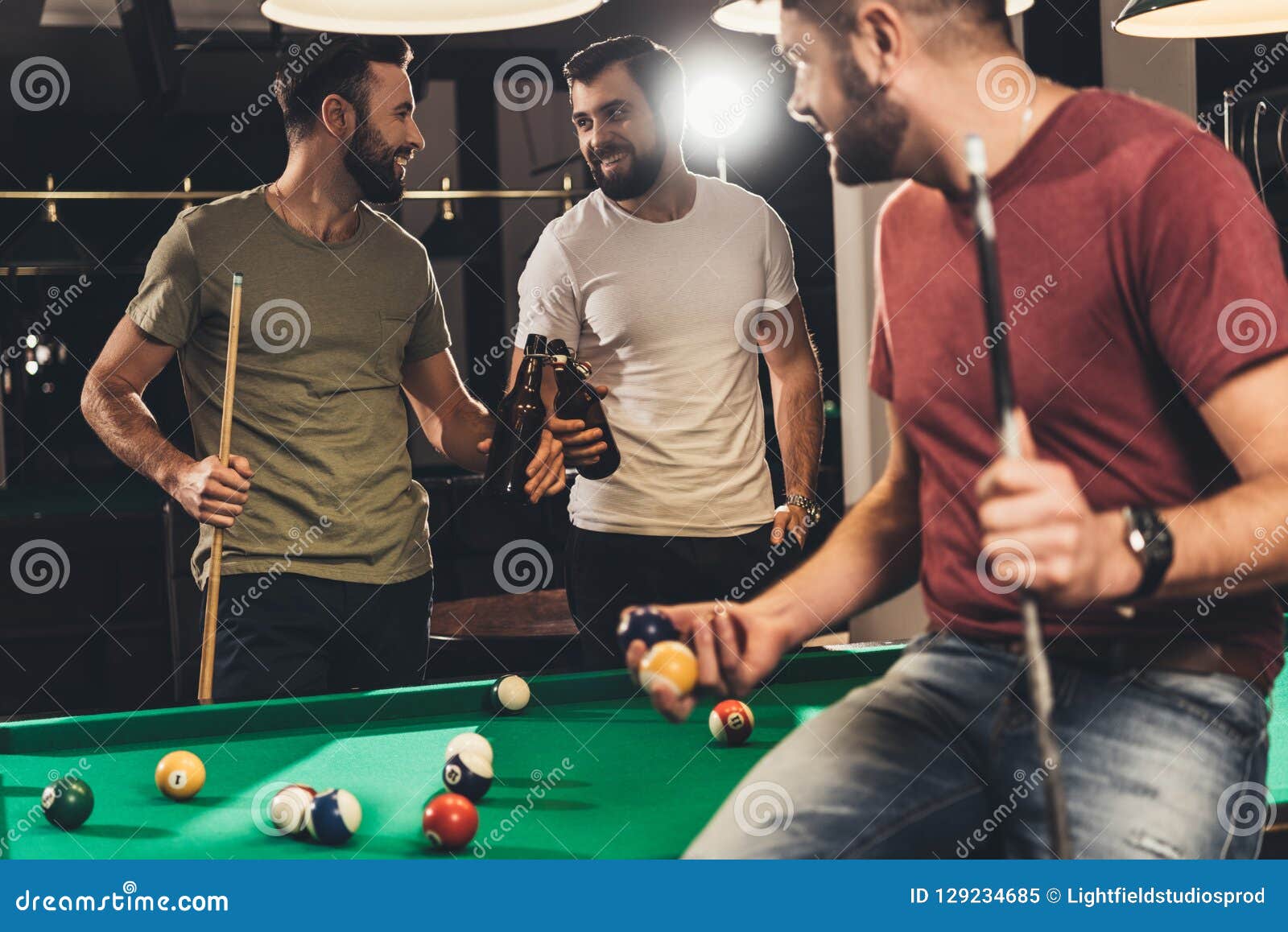 young caucasian men drinking beer beside billiard table