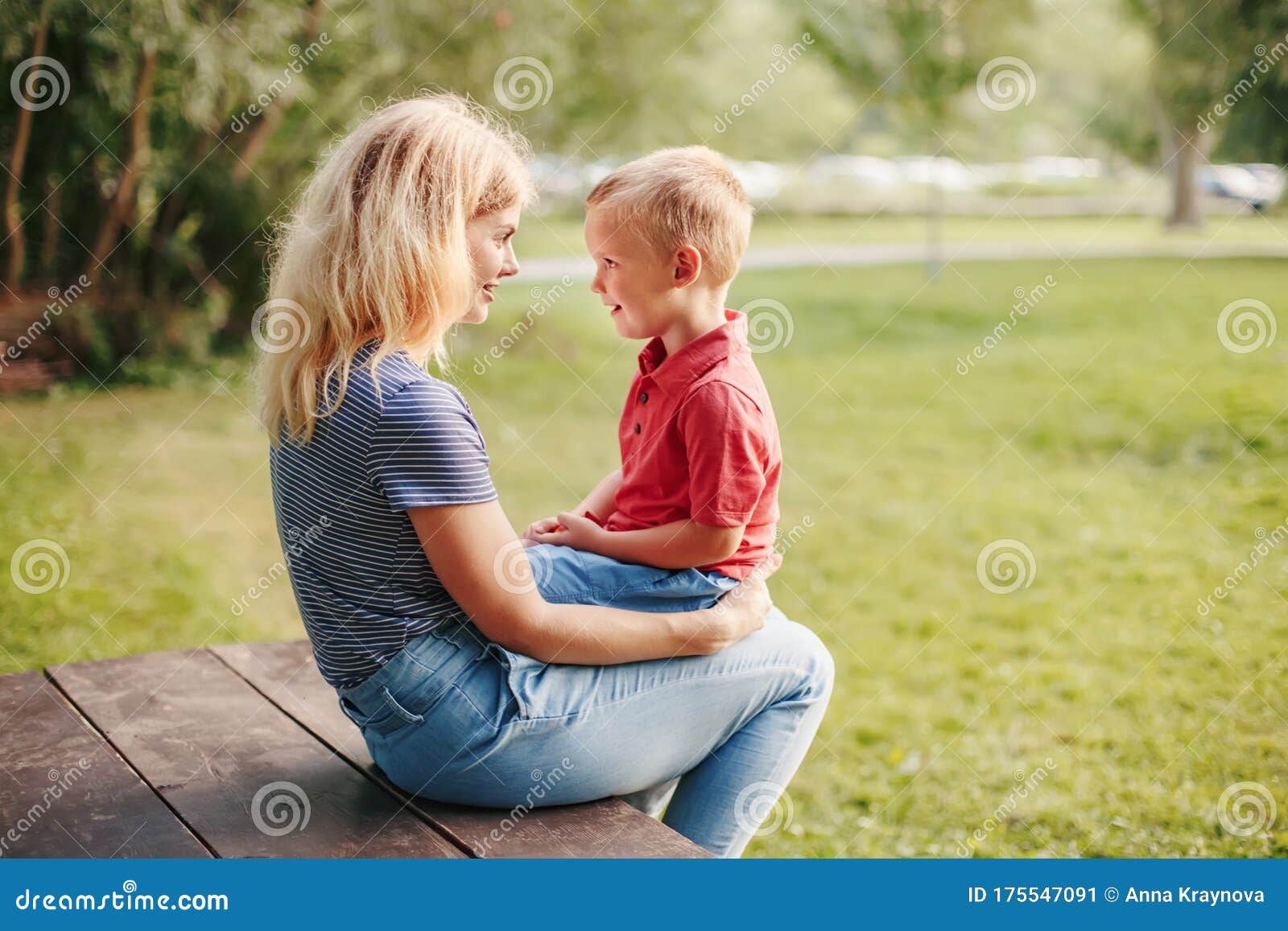 young caucasian mother and boy toddler son sitting together face to face. family mom and child talking communicating outdoor on a