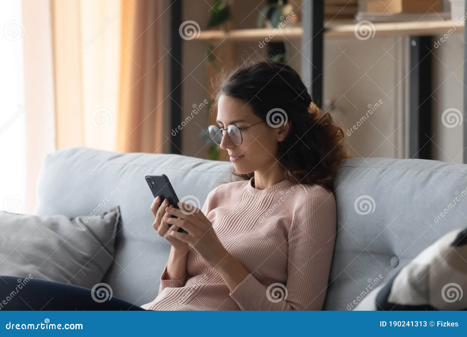 caucasian woman in glasses using cellphone at home