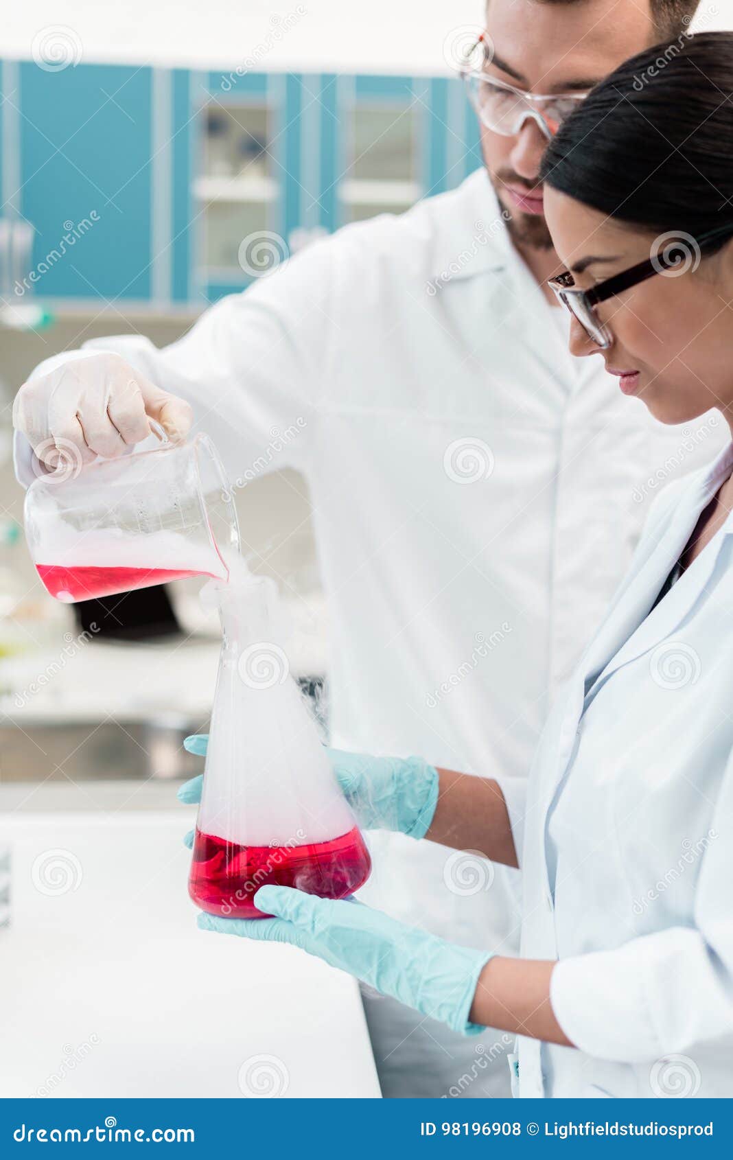 Young Chemists in Eyeglasses and White Coats Making Experiment with