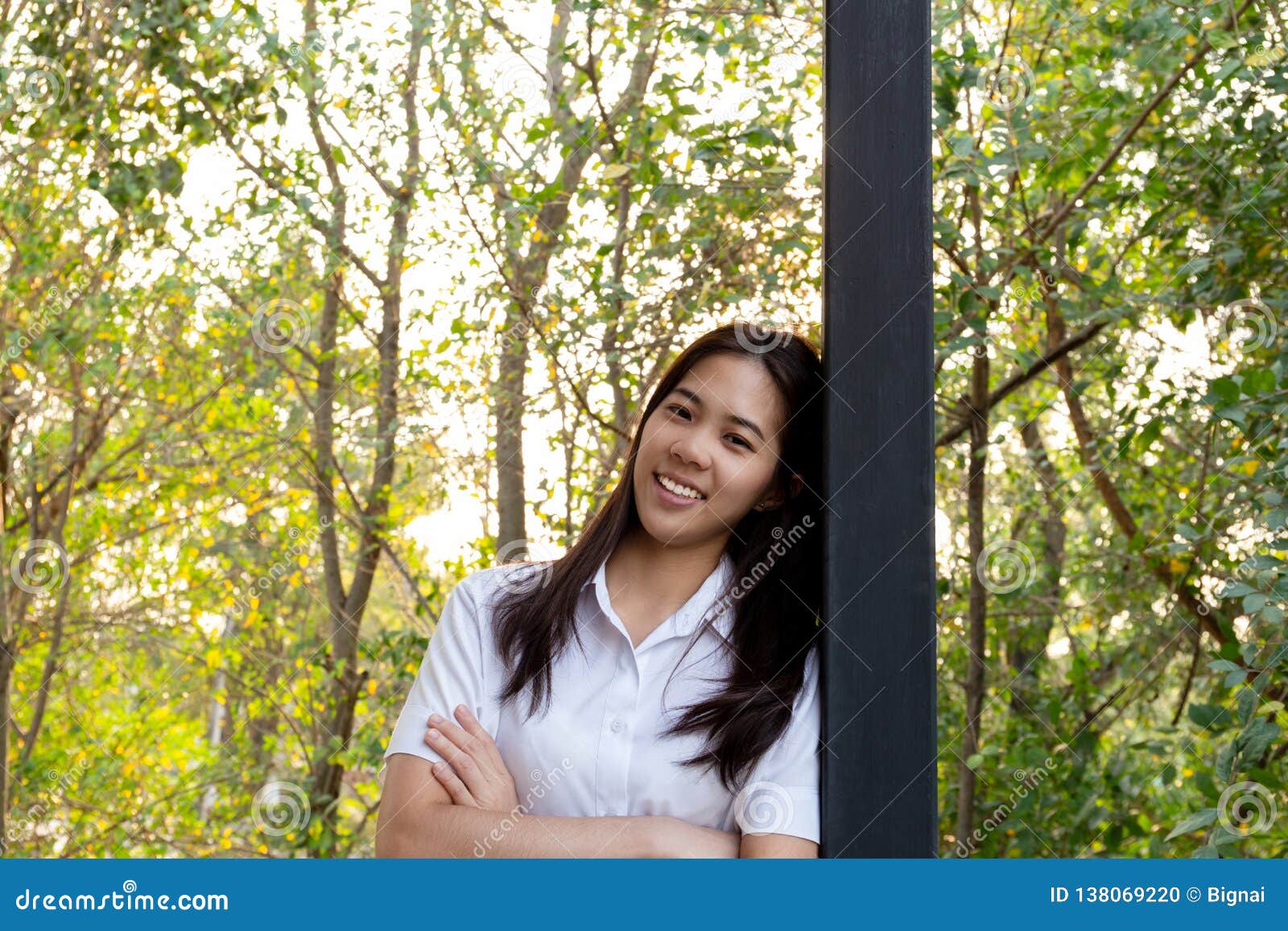 young collage woman smiling with arms folded with nauter sunlight.