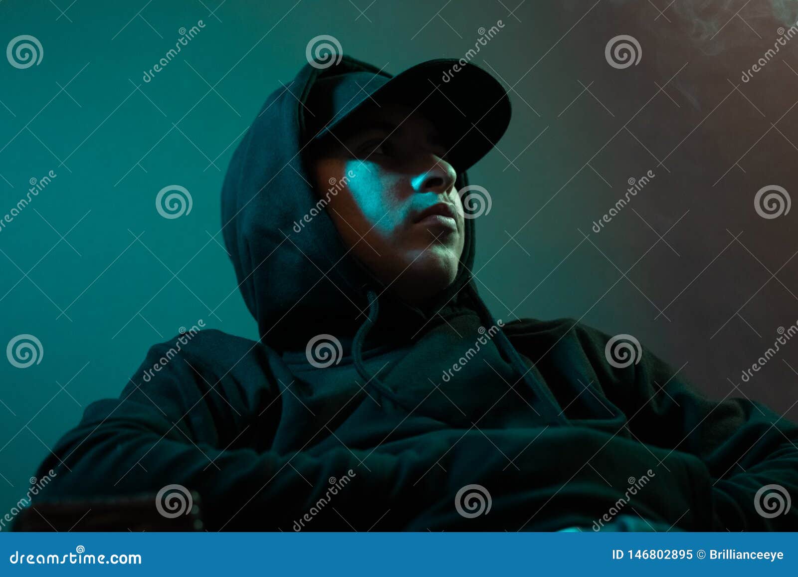 Young Cool Rapper with Black Hoodie and Cap Looking Sideways Stock