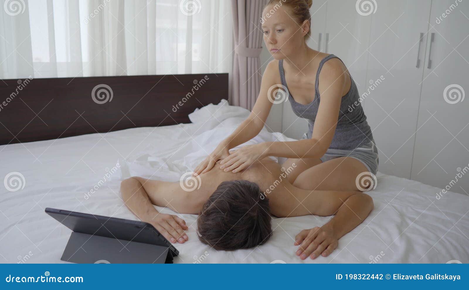 A Young Couple in the Bedroom. Woman Learns How To Perform a Body Massage  for a Man by Watching an Online Education Stock Footage - Video of indoors,  people: 198322442