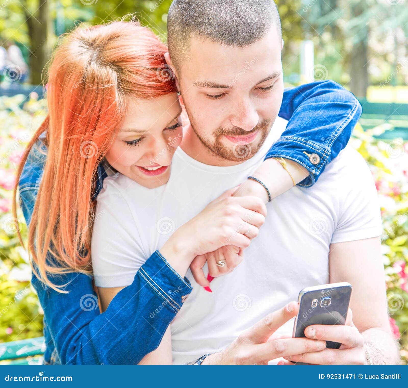 young couple with cellphone at the park