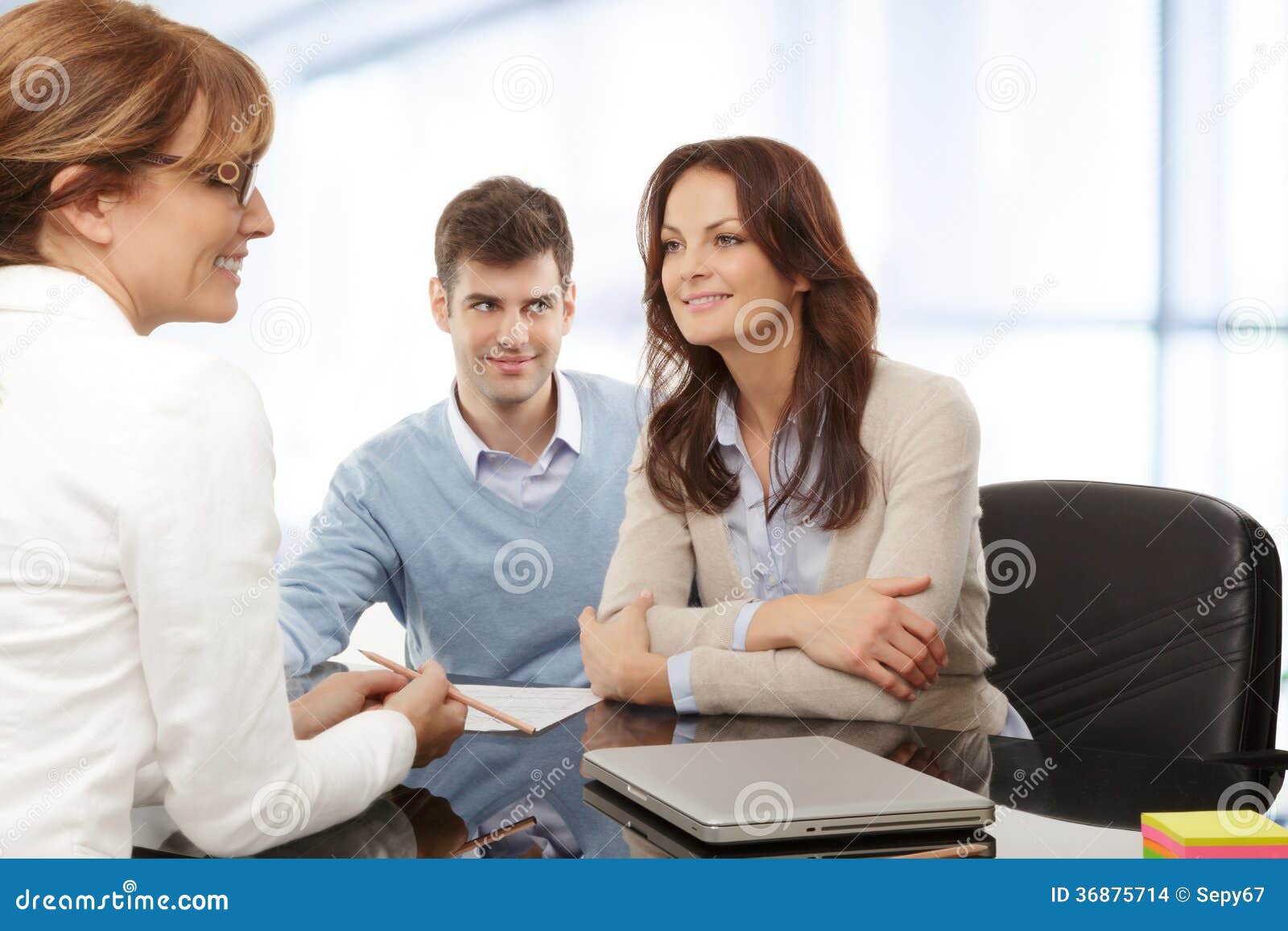  A couple is sitting at a desk having a conversation with a financial advisor about financial planning.