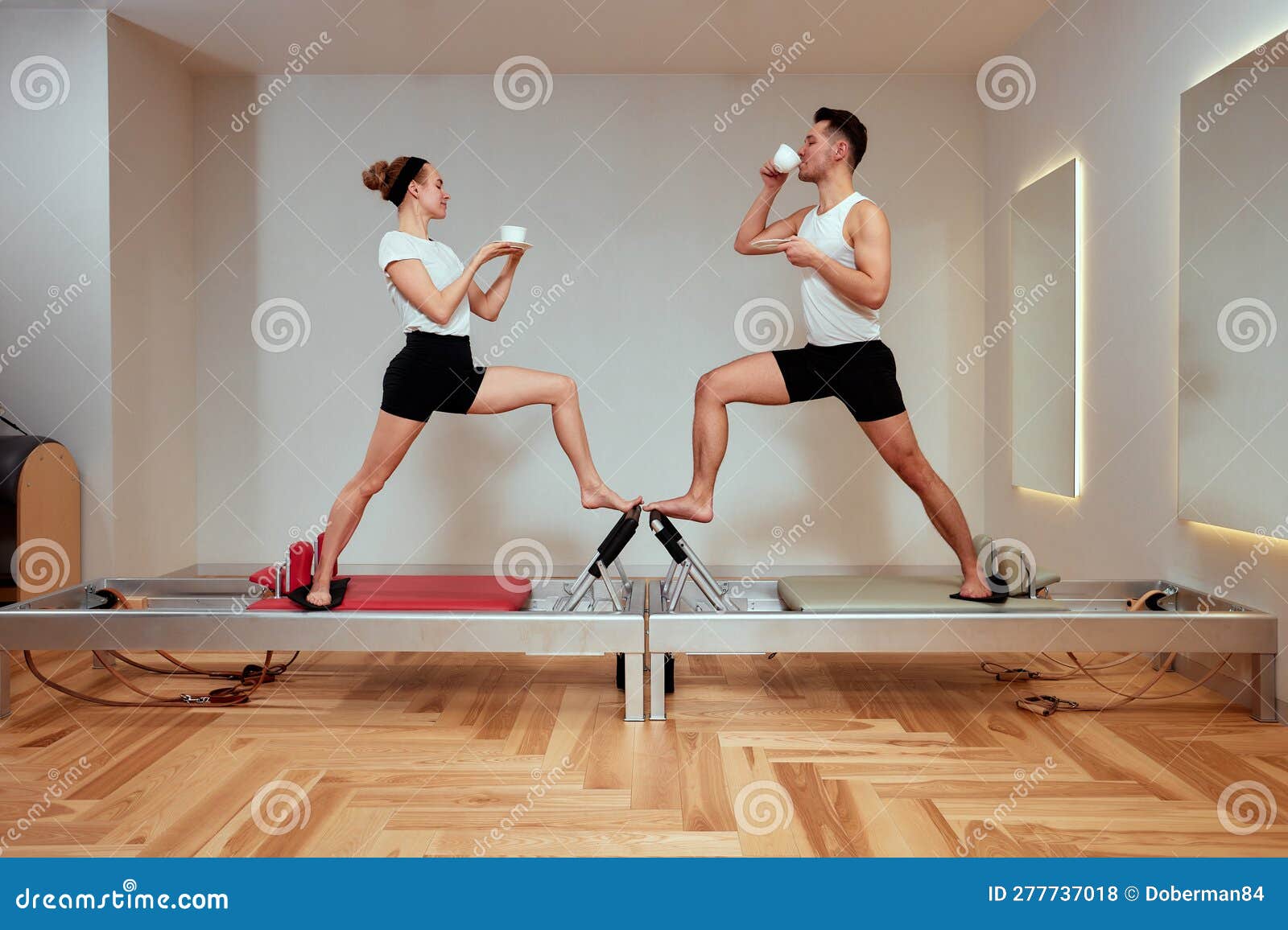 A Young Couple Doing Pilates on a Reformer and Drinking Coffee from