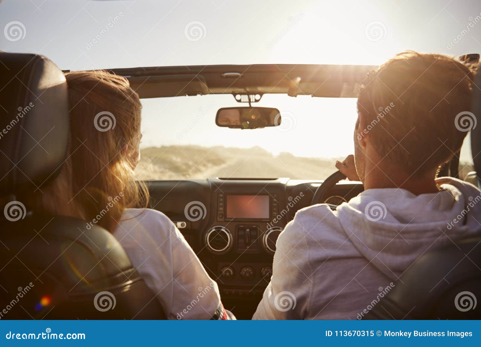 young couple driving with sunroof open, rear passenger pov