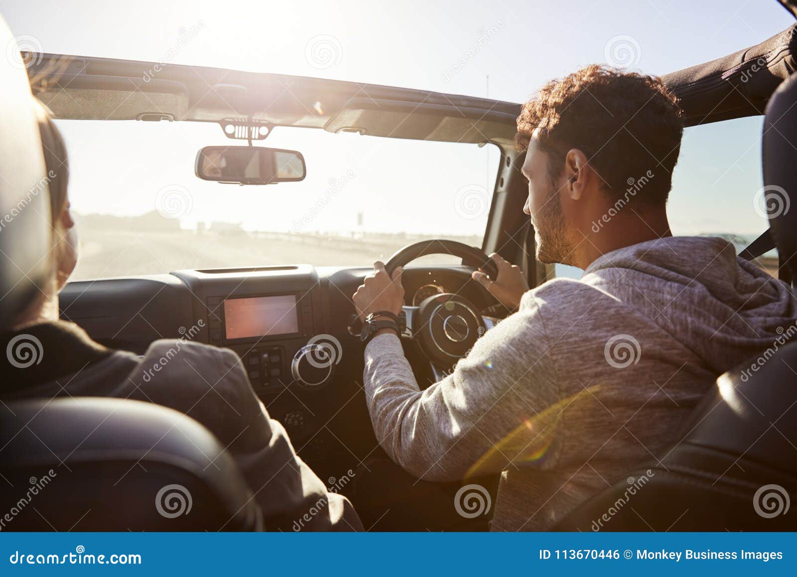 young couple driving with sunroof open, rear passenger pov