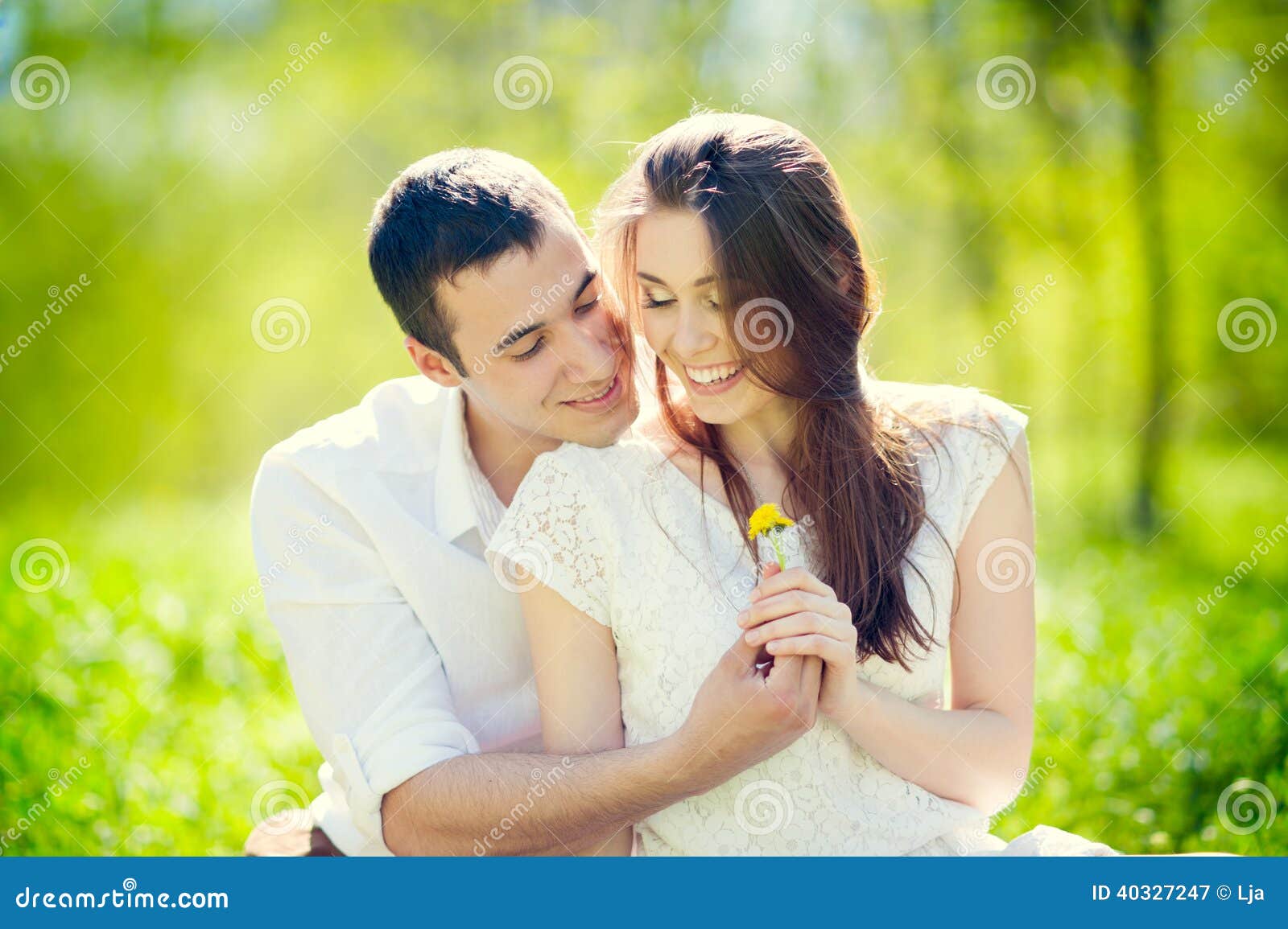 Happy Smiling Couple in love. Young Couple Lying on Grass Outdoor