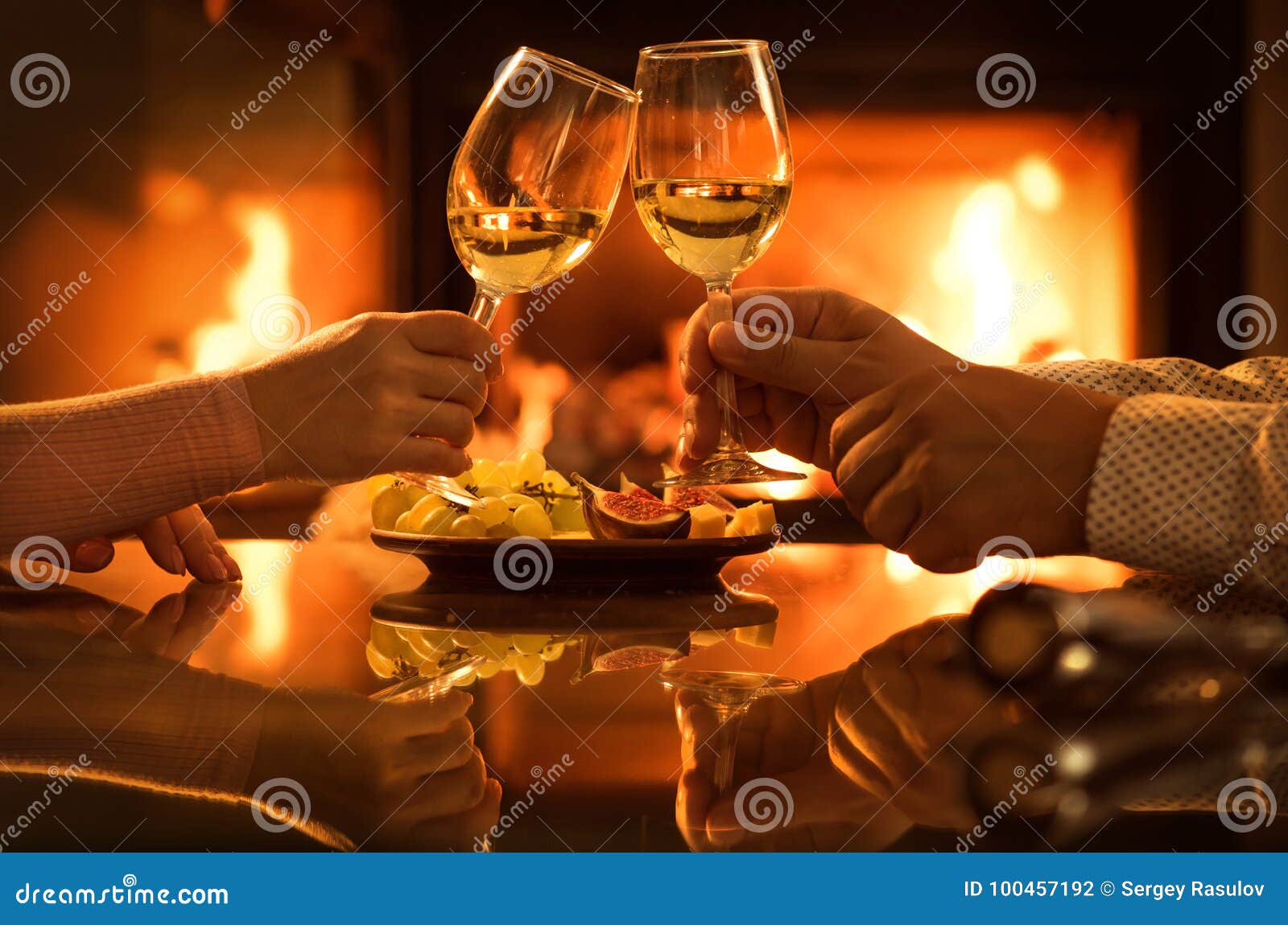 young couple have romantic dinner with wine over fireplace background.