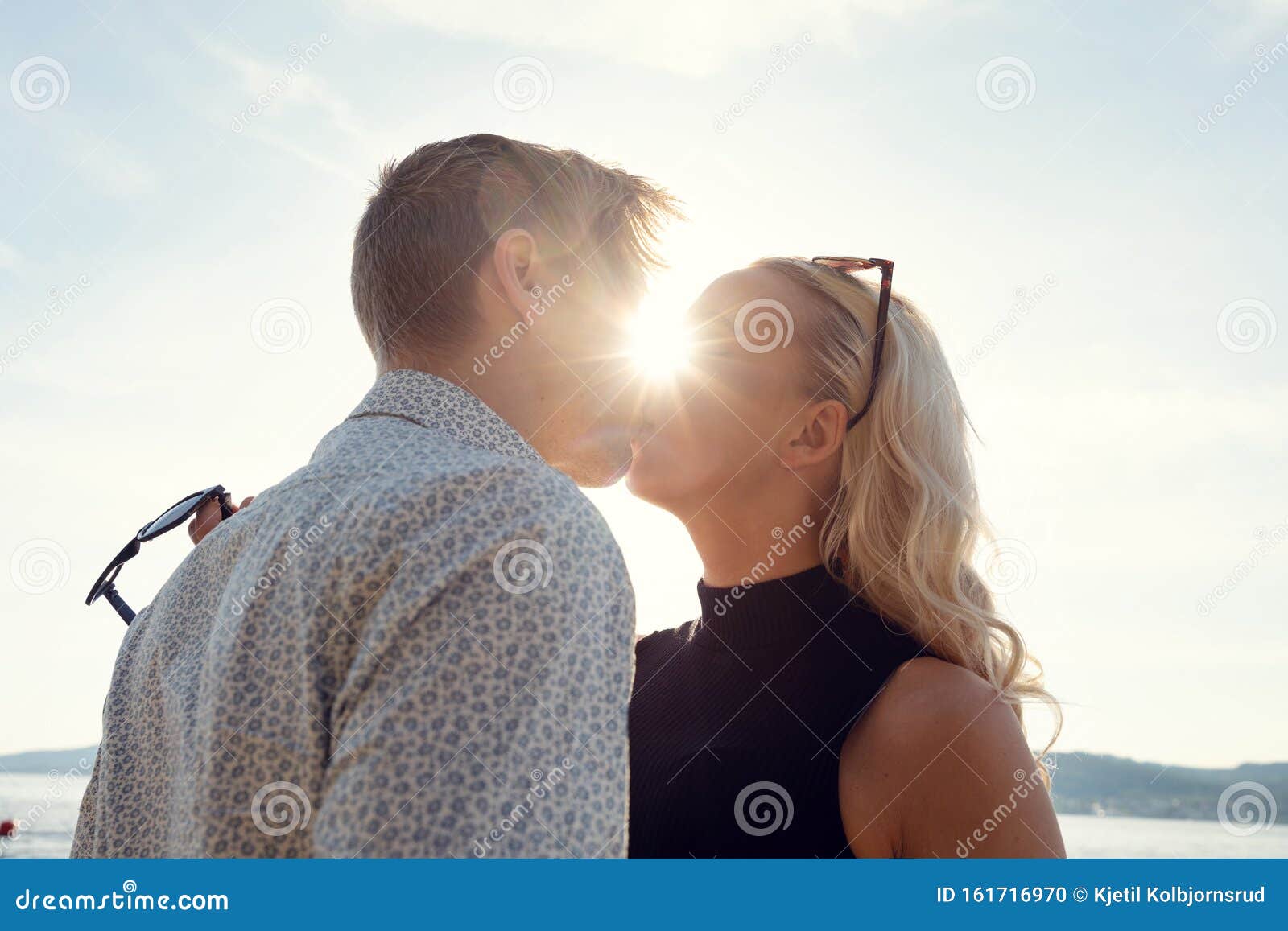 Young Couple Kissing Against Sun At Beach Stock Photo Image Of Smooching Casual