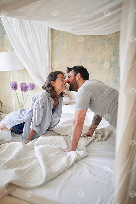 Young Couple Kissing In The Bedroom While Making Bed In The Morning Bedroom Morning