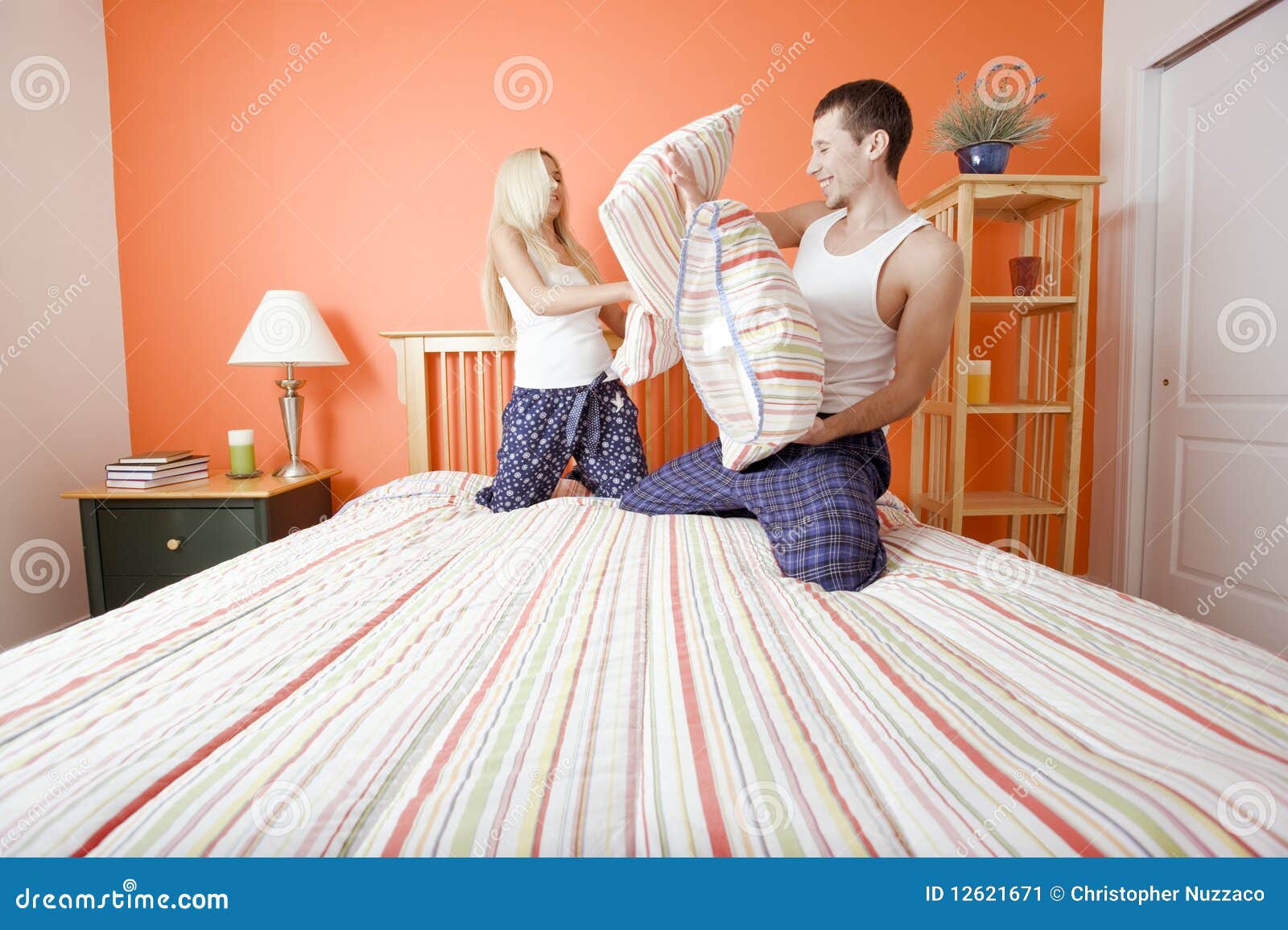 Young Couple Kneeling on Bed Having a Pillow Fight Stock Image Image