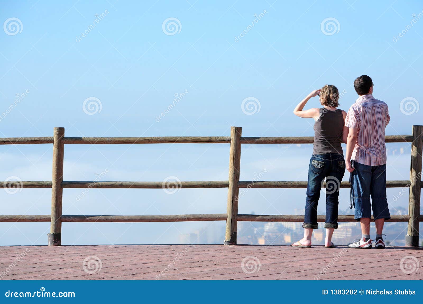 young couple looking out to sea from high viewpoint
