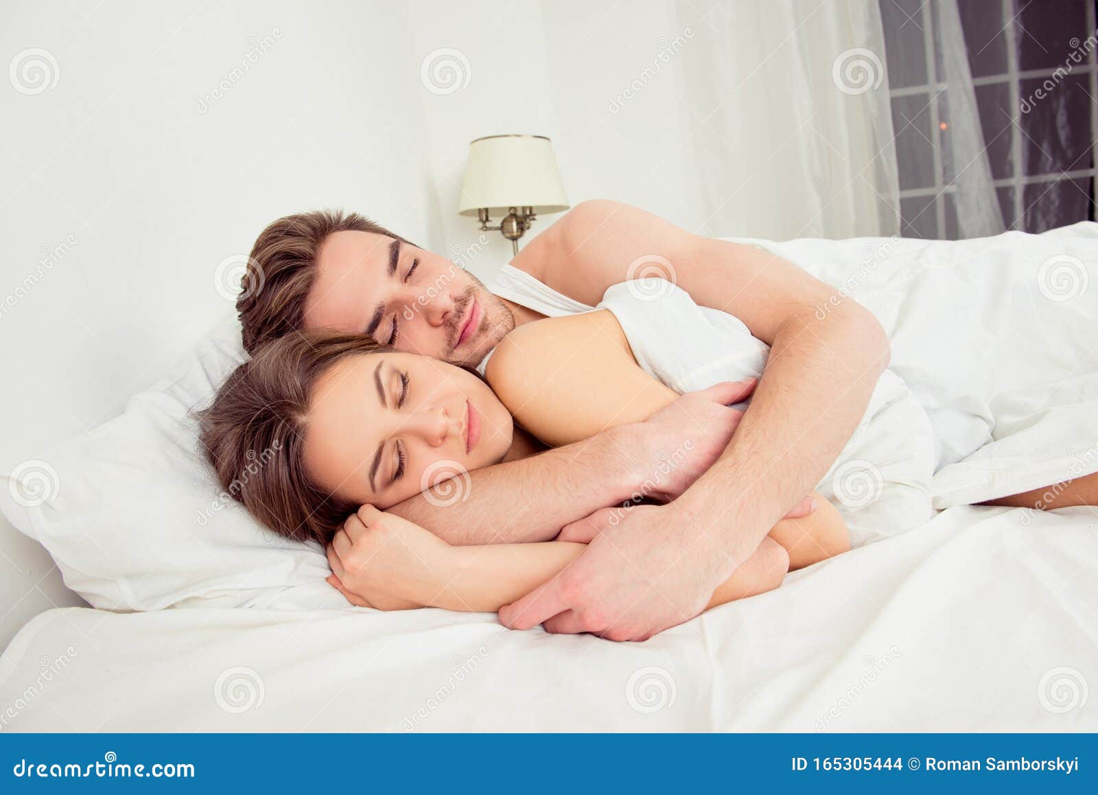 Young couple in love sleeping in the bedroom hugging cuddling.