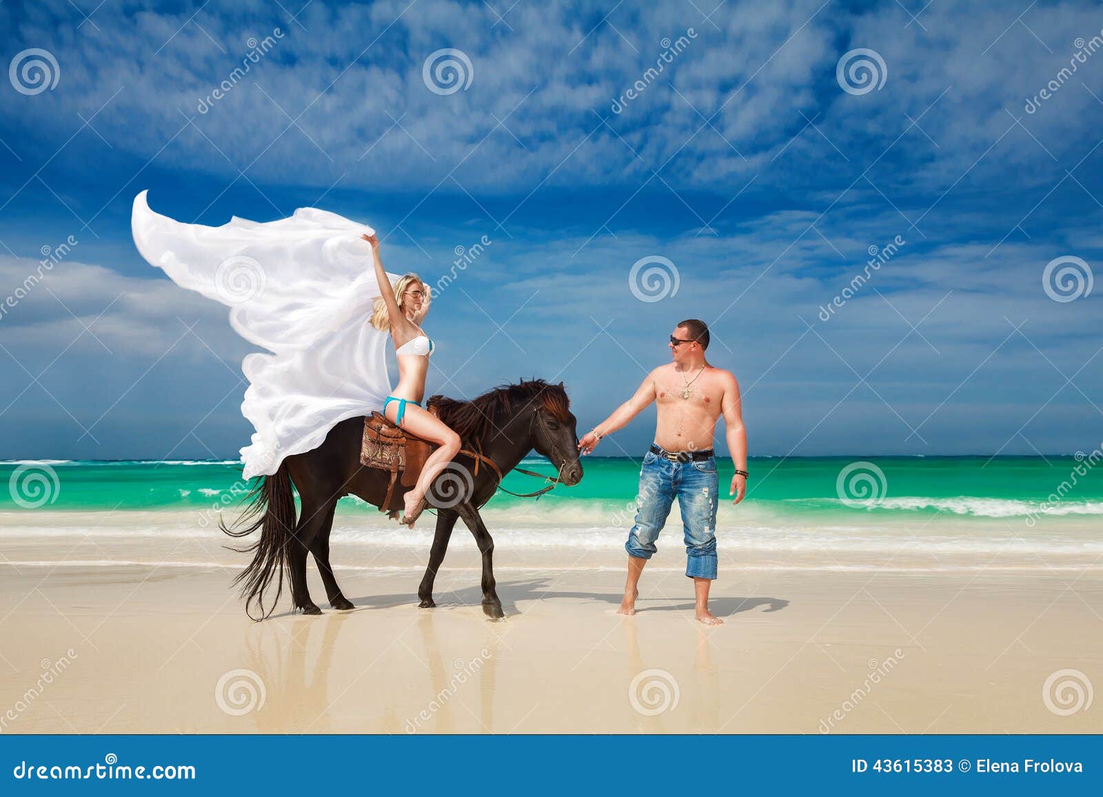 Young couple in love walking with the horse on a tropical beach. Tropical sea in the background. Summer vacation