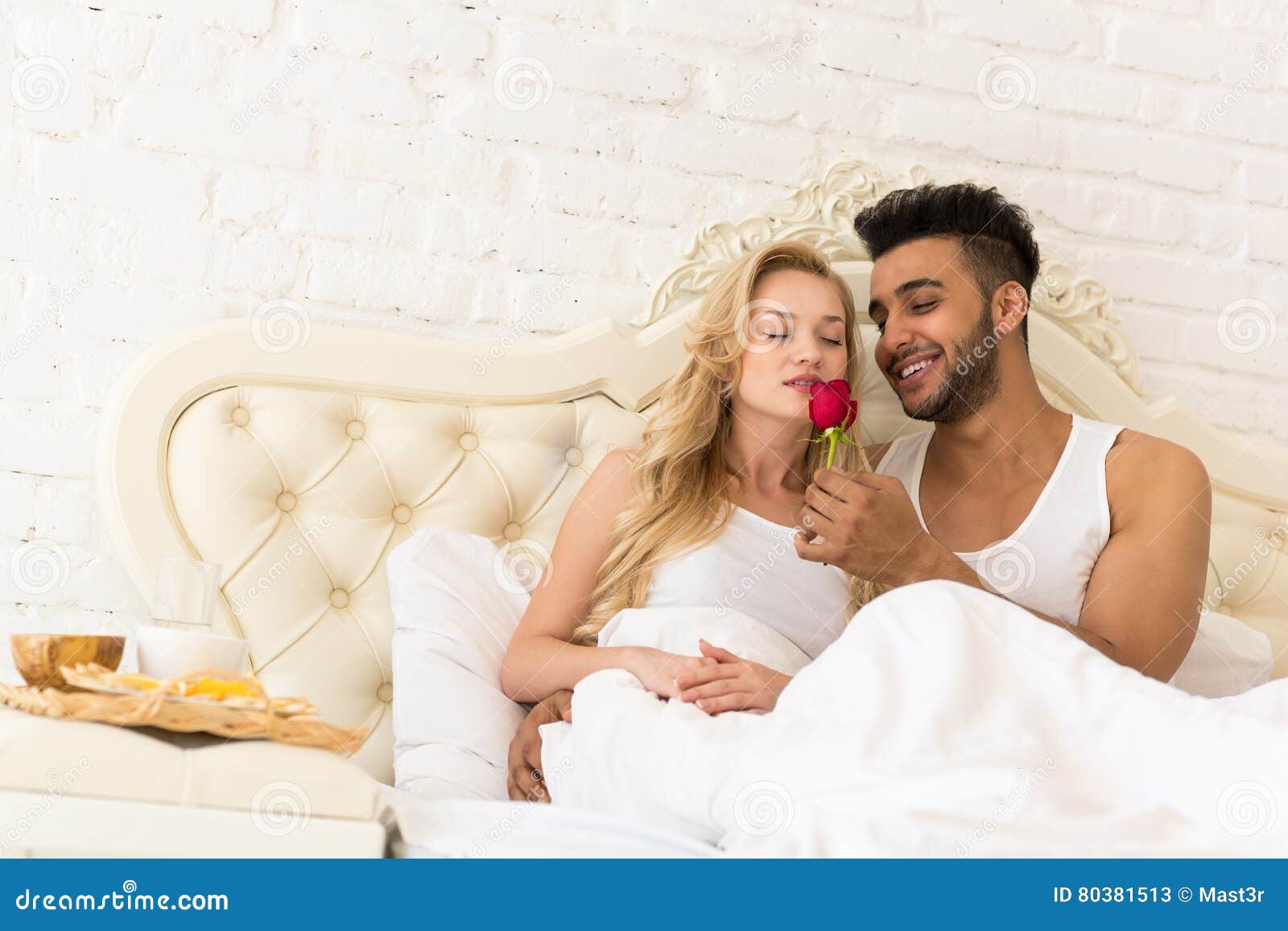 Young Couple Lying In Bed Eat Breakfast Morning With Red Rose