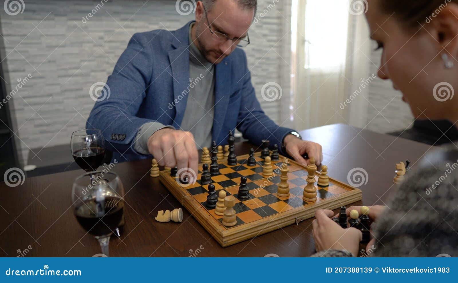 young couple playing chess while sitting at table at home - Unpacked